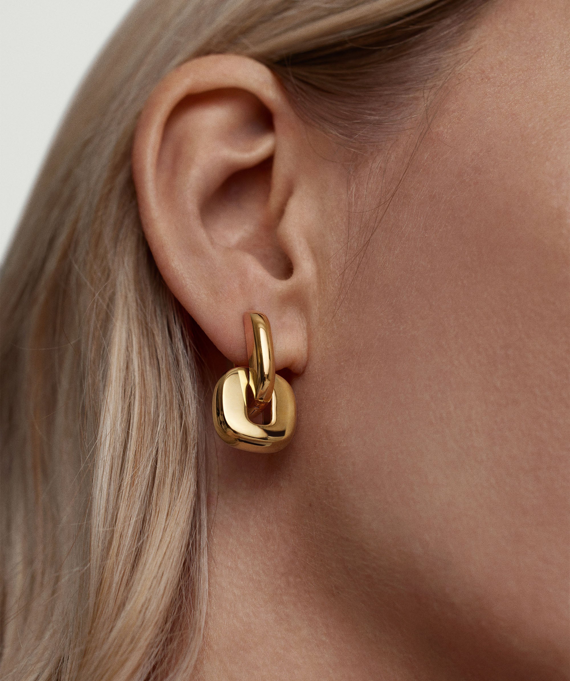 Close-up of a woman's ear showcasing the Stevie Hoops and Links Mixed Metals Bundle, featuring a gold hoop with interchangeable, reversible links.