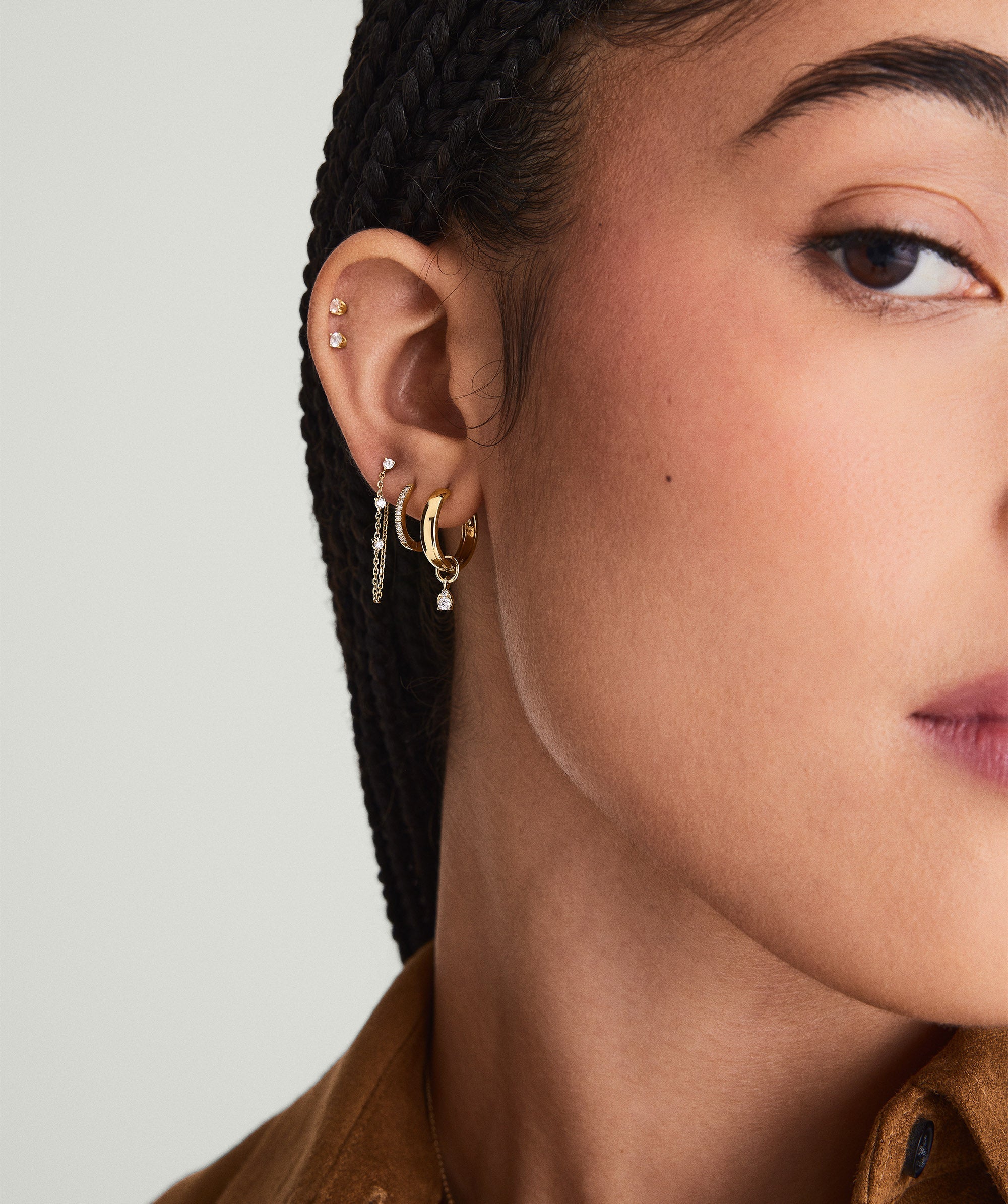 Mini Pear Diamond Hoop Charm on a woman's ear. Close-up shows the 14k solid gold earring with a pear-shaped diamond.