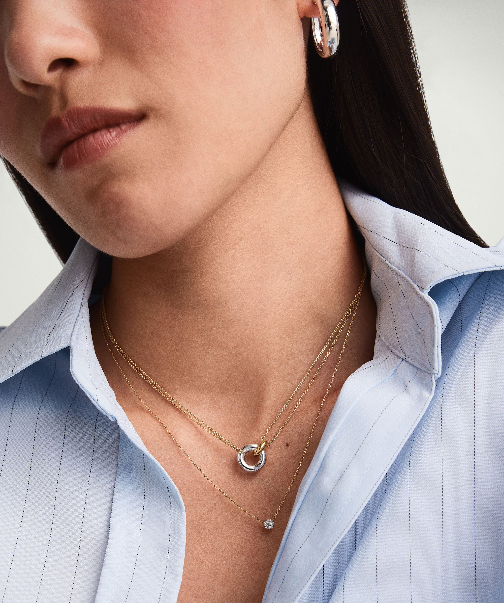 Linked Two-Tone Necklace: A woman wearing a necklace with two interlinked rings, symbolizing personal bonds, handcrafted in sterling silver and gold vermeil.