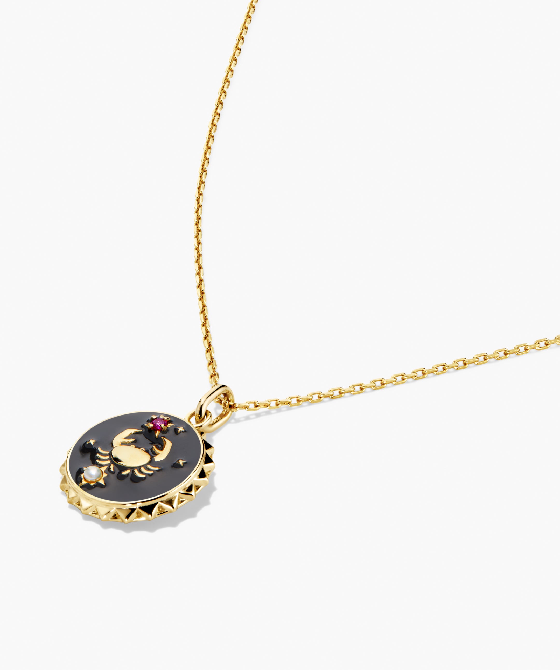 Cosmic Pendant Necklace with gold crab motif on black enamel, studded border, pinkish-red gemstone, and pearl accent, symbolizing Cancer zodiac.