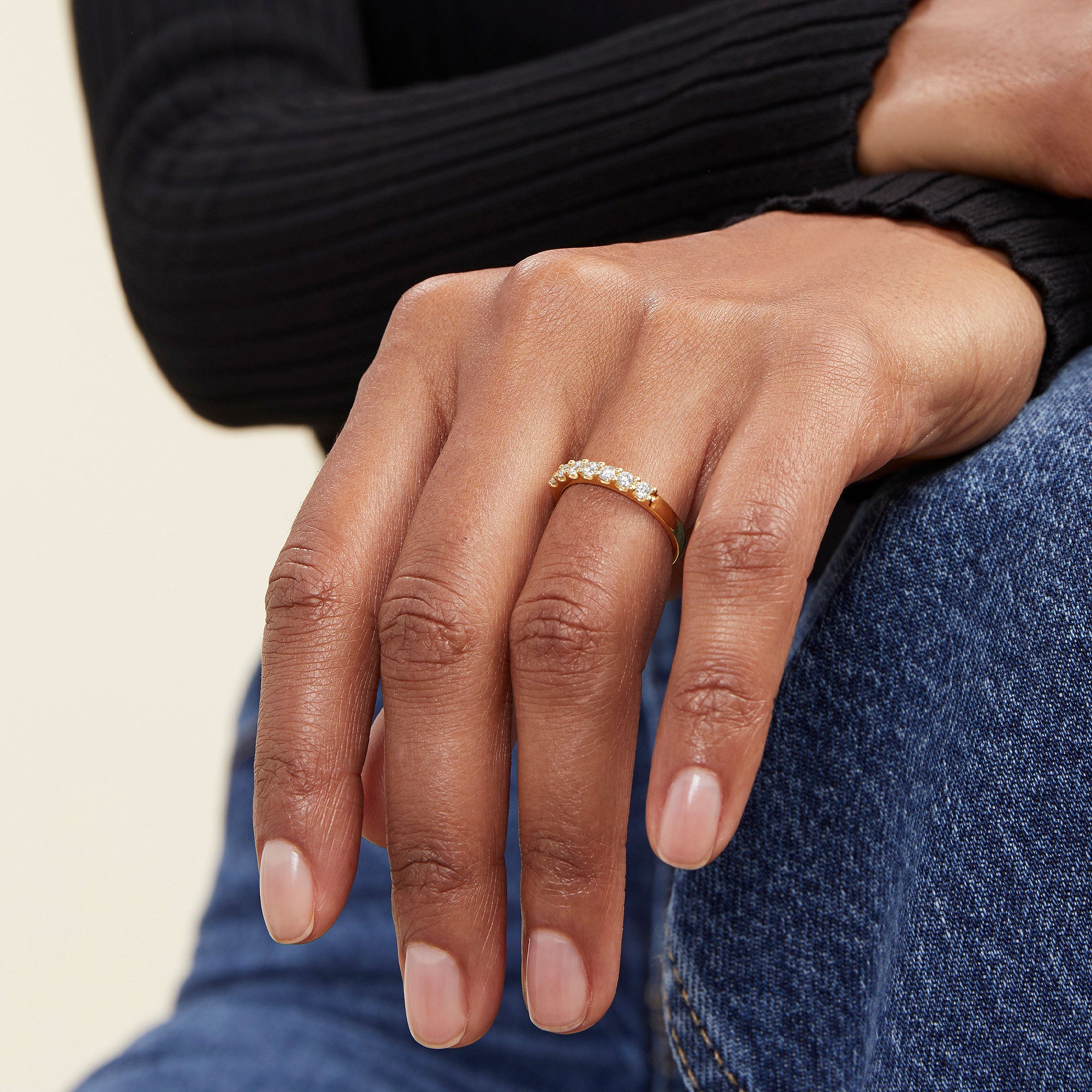 Bold Diamond Half Eternity Ring: A close-up of a hand wearing a handcrafted 14k solid gold ring with seven round cut diamonds.