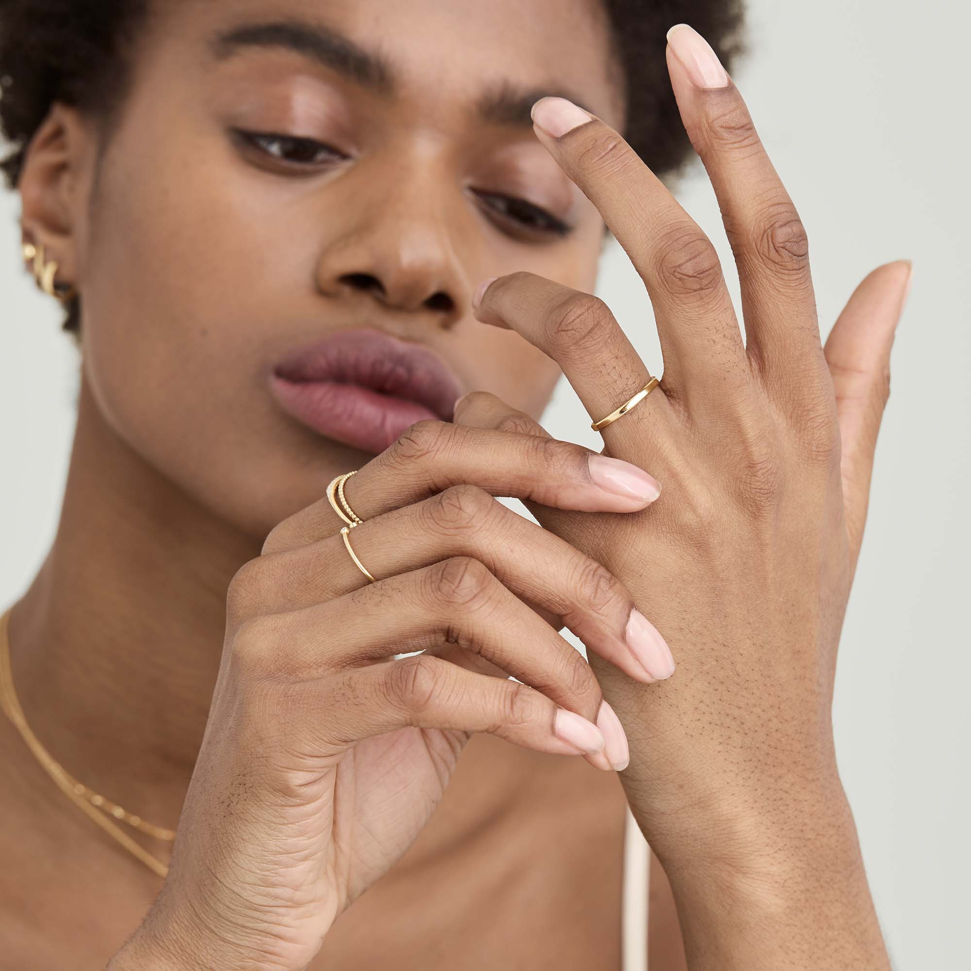 Woman with curly hair wearing 2mm Curve Band on her finger, showcasing its lightweight design.