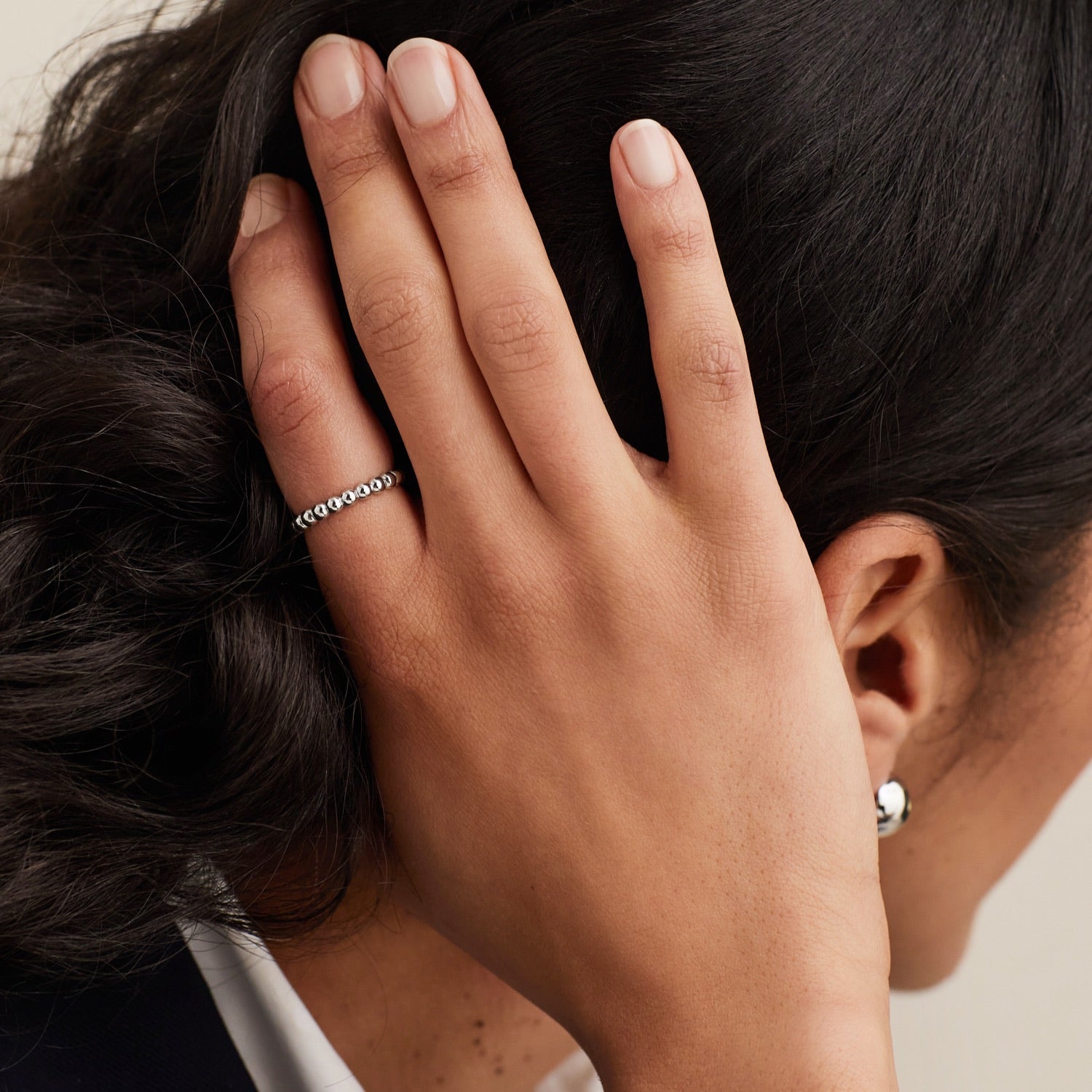 A woman's hand adorned with a Metallic Sphere Ring in sterling silver, showcasing its bold design and elegant craftsmanship.