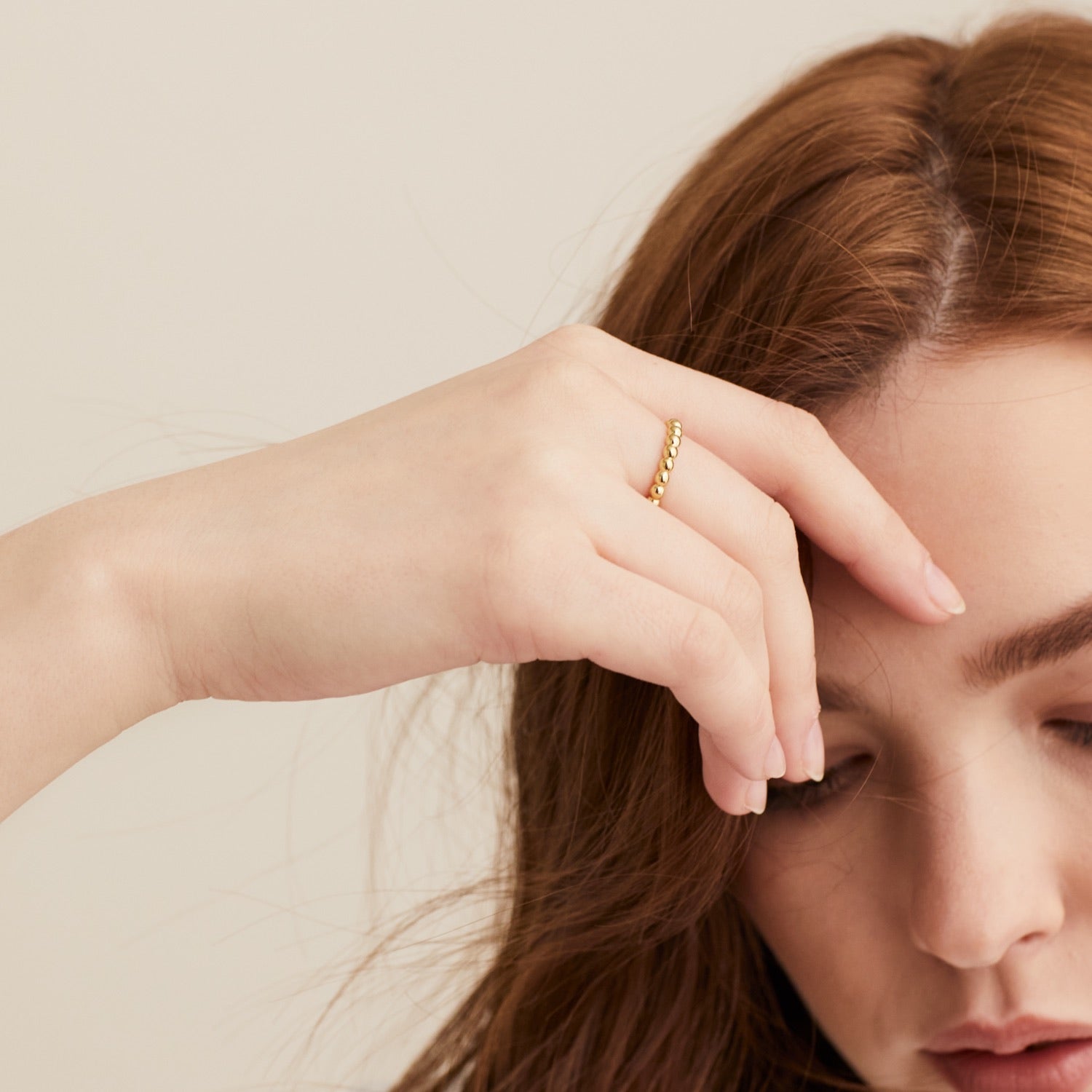 Woman wearing the Metallic Sphere Ring in 18k gold vermeil, her hand on forehead, showcasing the ring's bold design.