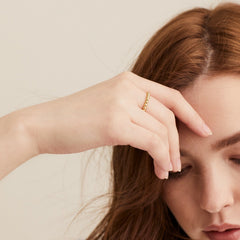 Woman wearing the Metallic Sphere Ring in 18k gold vermeil, her hand on forehead, showcasing the ring's bold design.