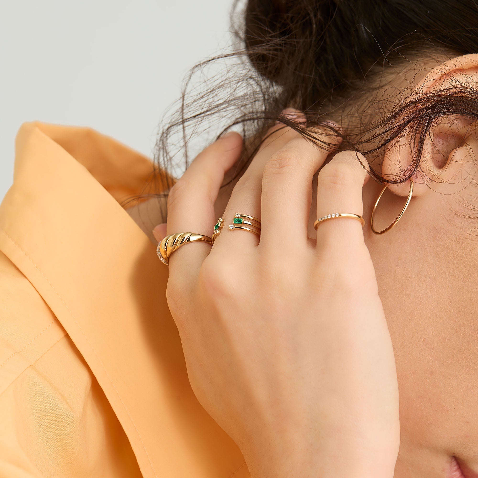 Close-up of a woman's hand showcasing a 14k gold Baguette Emerald Open Ring with unique, handcrafted emeralds.