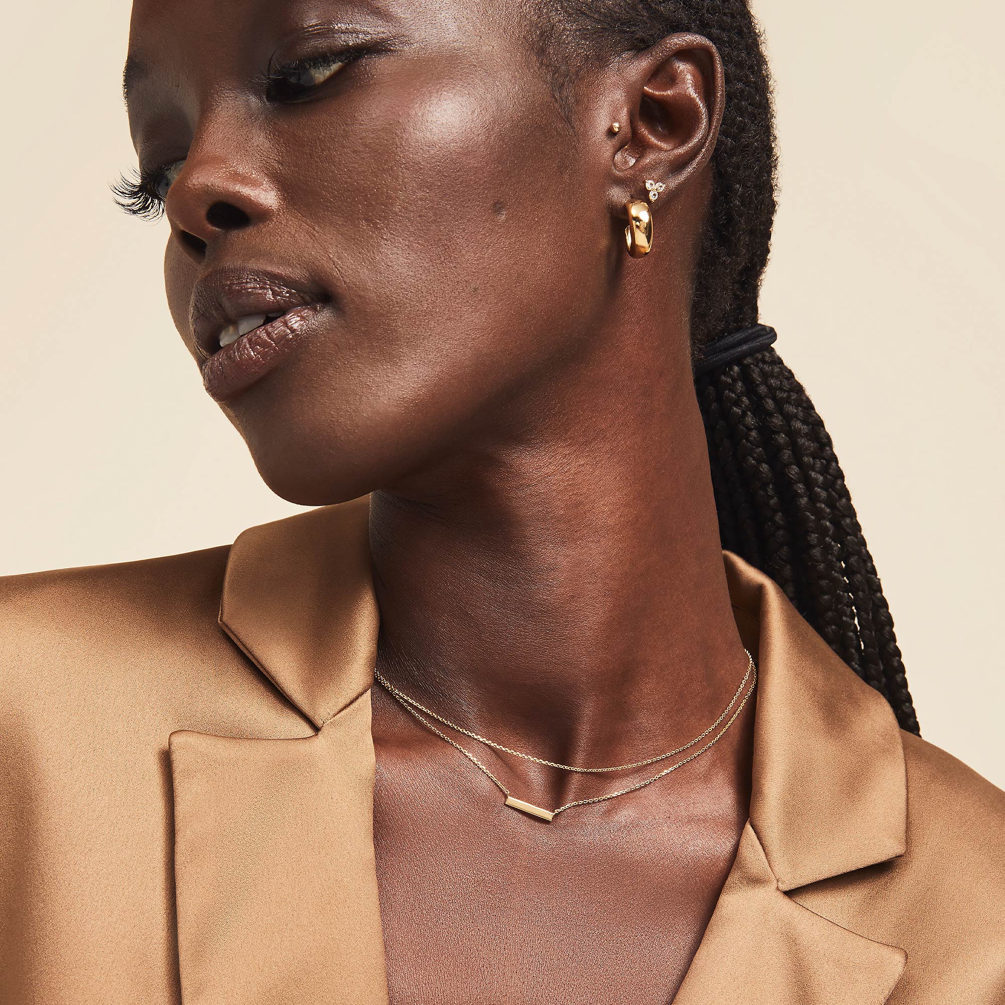 Layered Bar Necklace on a woman's neck, elegantly complementing her braided hairstyle and gold jacket, perfect for everyday wear.