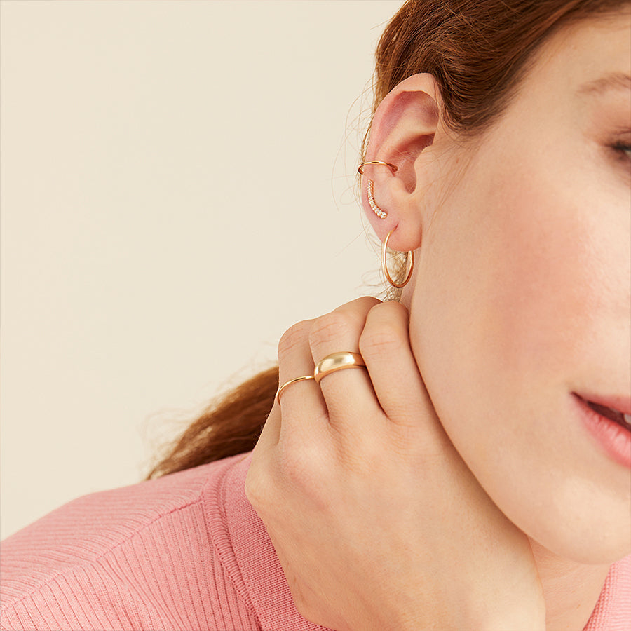 Close-up of a woman's ear wearing PavÃ© Diamond Climbers, showcasing handcrafted 14k solid gold earrings set with pavÃ© diamonds.