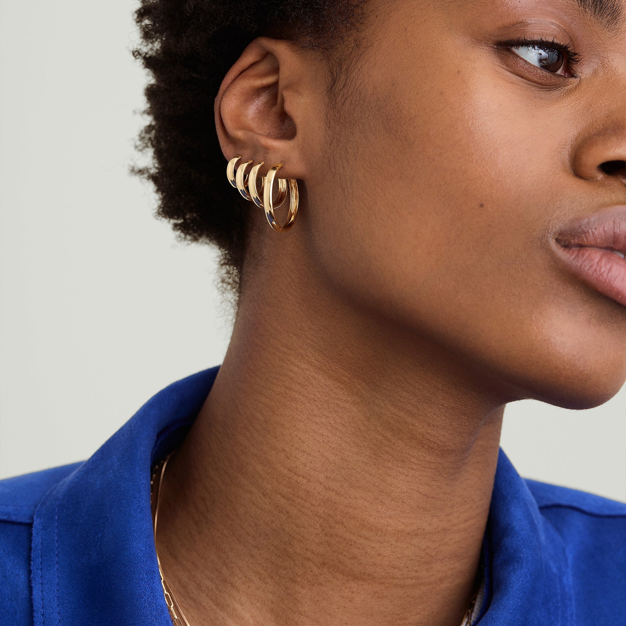 Bold Large Hoops: A woman in a blue shirt showcases large, handcrafted hoops made from recycled 14k solid gold.