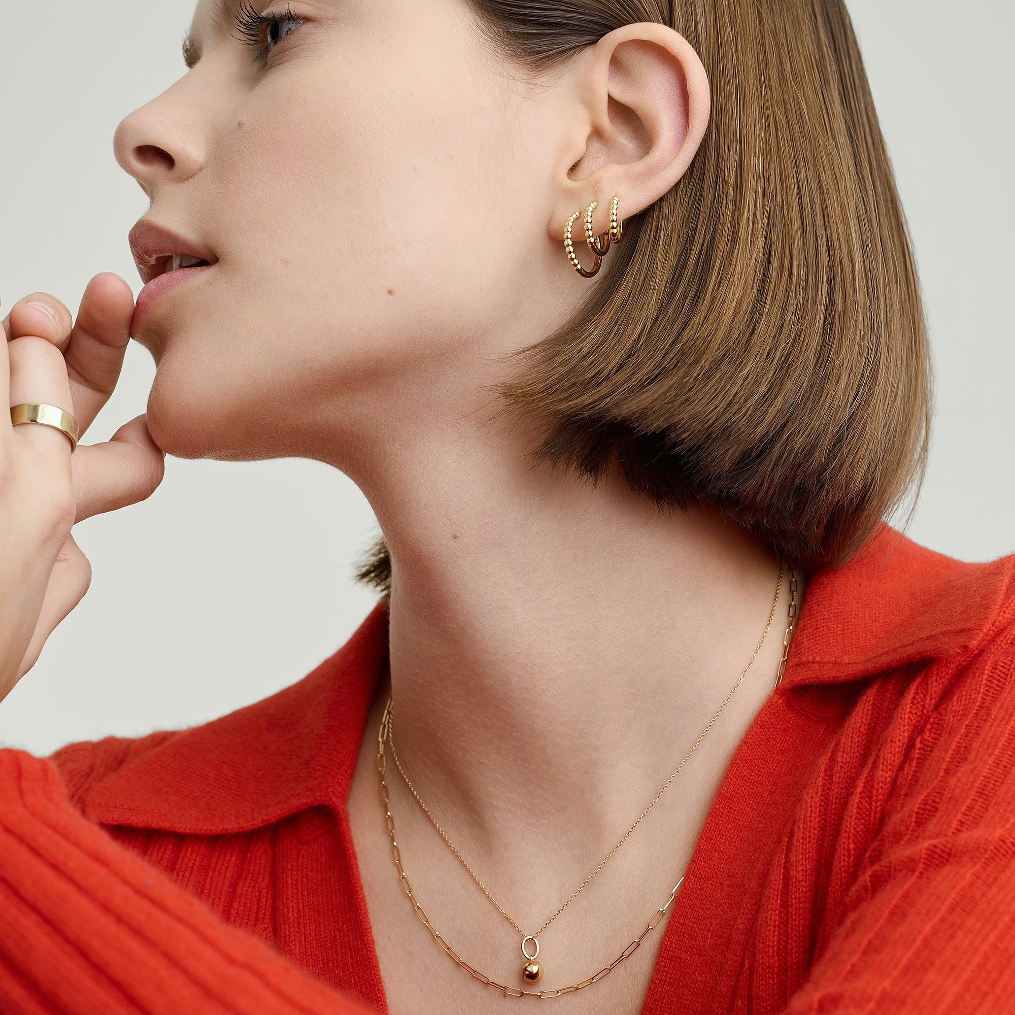 Woman wearing Beaded Small Hoops in recycled 14k solid gold, paired with a gold necklace, showcasing the earrings' intricate beaded design and craftsmanship.