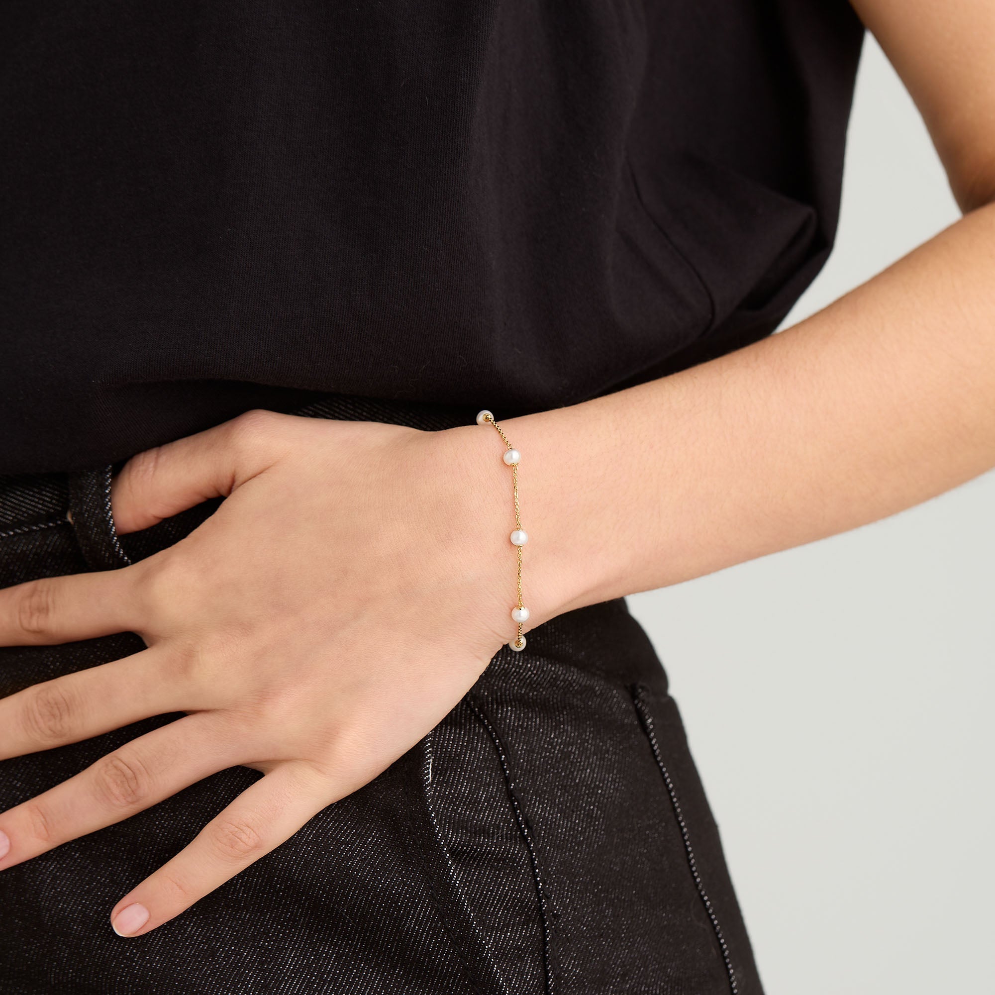 Close-up of a person wearing the Mini Pearl Satellite Bracelet, featuring freshwater pearls on a gold vermeil chain, elegantly draped on the wrist.