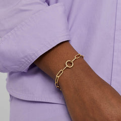 Person wearing the Paperclip Chain Charm Bracelet with a Stacker Clasp, showcasing three layered charms, handcrafted in 14k solid gold.