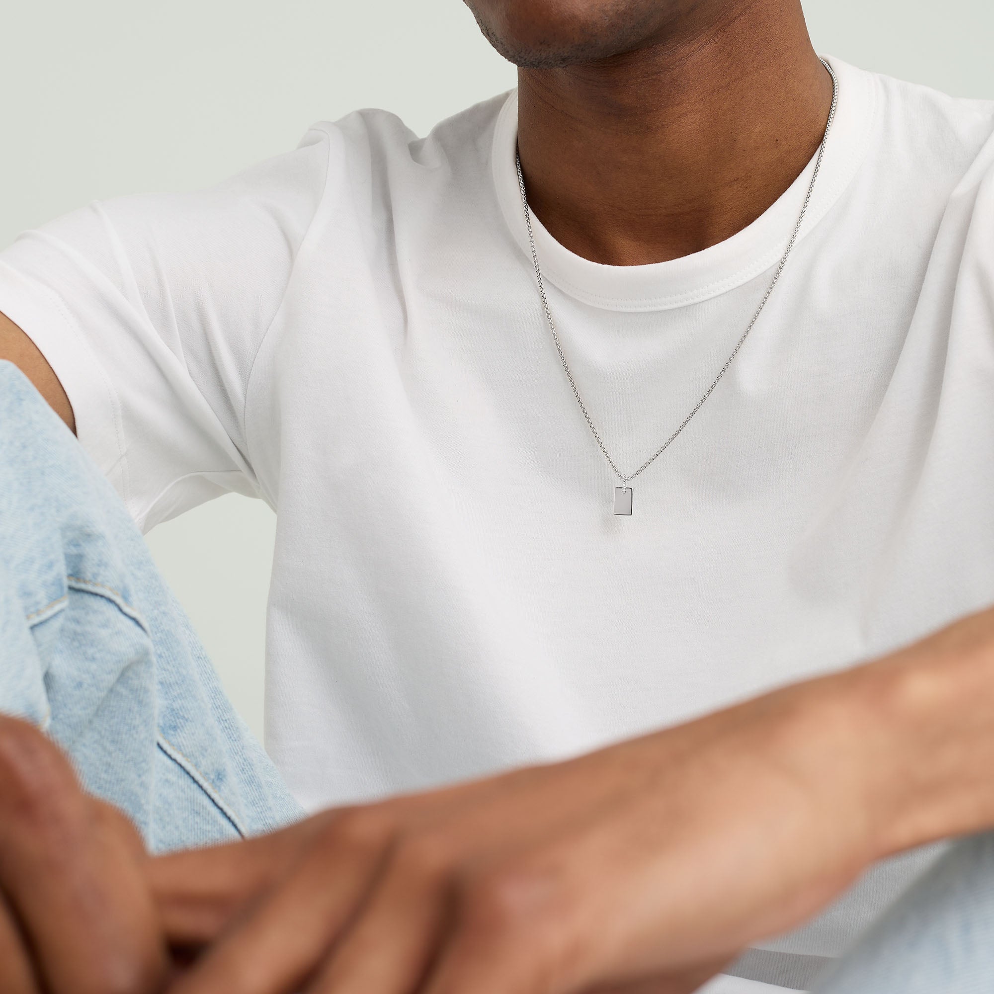 Close-up of a man wearing a white shirt, showcasing the Pave Diamond Bail Tag Charm Pendant with pavÃ© diamond-set bail on a necklace.