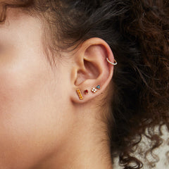 Close-up of a woman's ear wearing a Cartilage PavÃ© Diamond Mini Hoop in 14k solid gold with a hinge clasp and pavÃ© diamond setting.