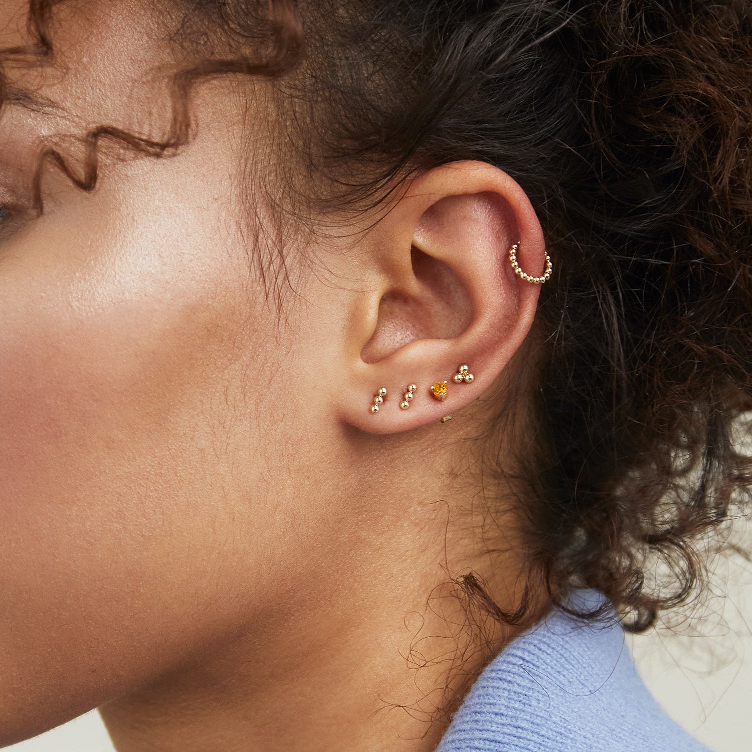 Close-up of a woman's ear wearing Spheres Bar Studs, handcrafted in 14k solid gold, showcasing their elegant and minimalist design.