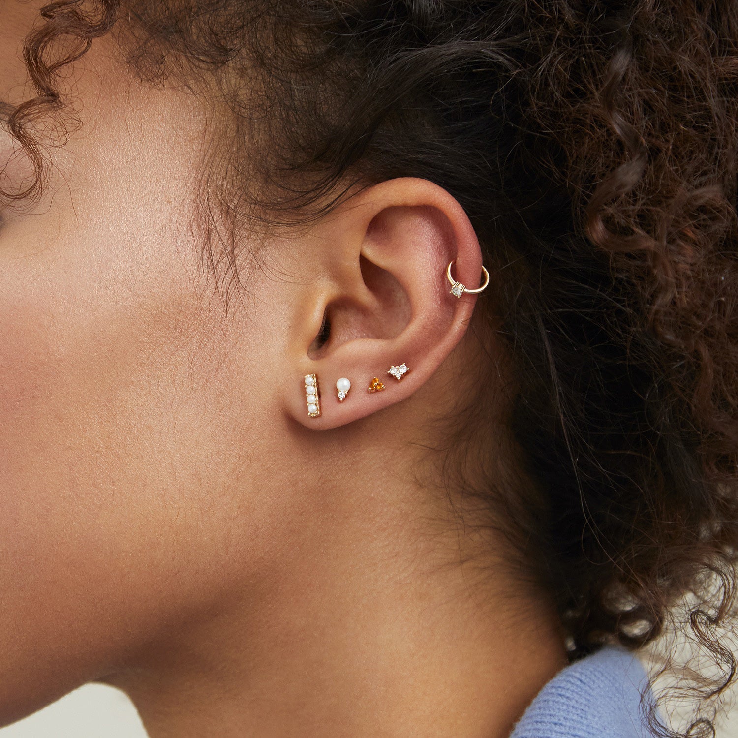 Close-up of a woman's ear adorned with Diamond Pearl Studs, featuring a 14k solid gold setting, diamonds, and a pearl.