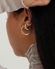 Close-up of a woman's ear showcasing the Tube Hoops Bundle, featuring Huggie, Medium, and Large Tube Hoops, highlighting fine jewelry as a fashion accessory.
