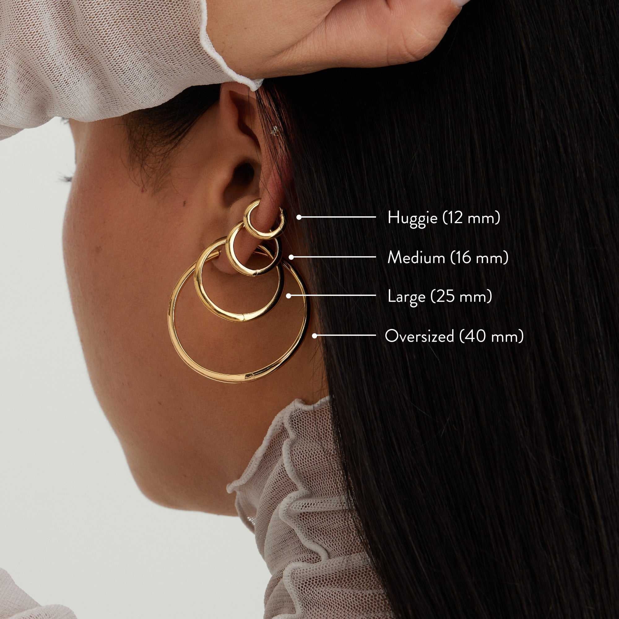 Close-up of a woman wearing Tube Oversized Hoops, showcasing bold and lightweight gold earrings with a clicker closure for comfort and security.