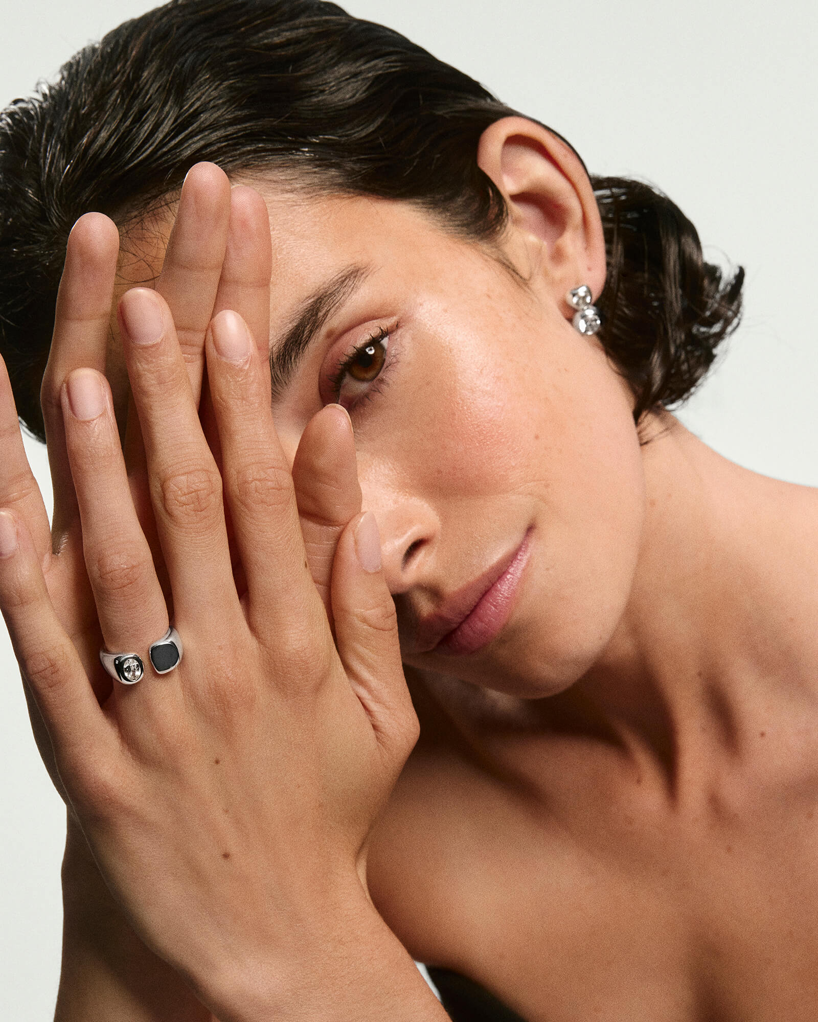 Young woman showcasing the Noa Open Signet Pinky Ring, featuring a gemstone in an open-faced band, alongside other striking silver jewelry, emphasizing modern elegance.