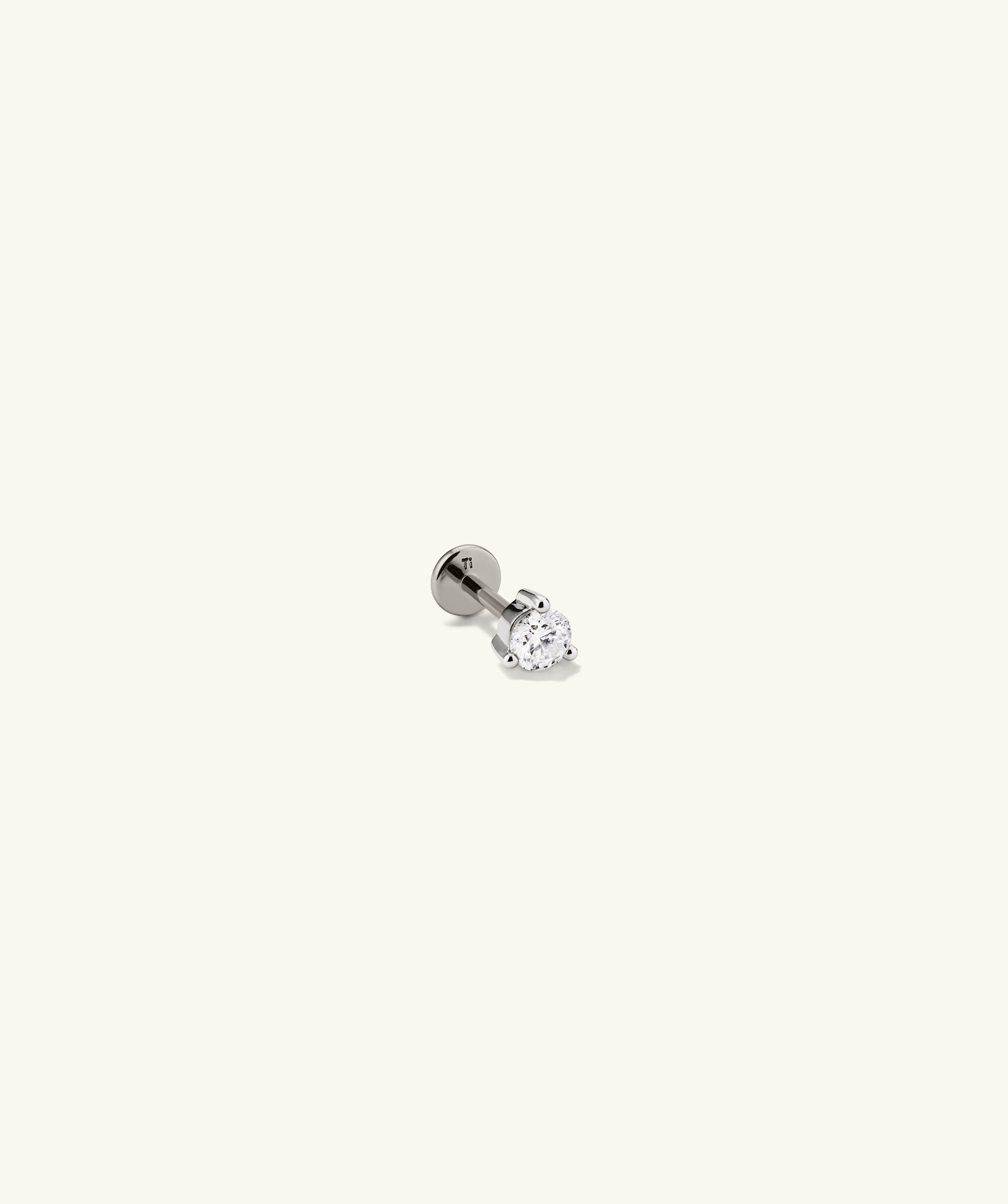 Close-up of Piercing Studio's Round Diamond Flat Back Stud, featuring a simple diamond set in metal, ideal for stacking.