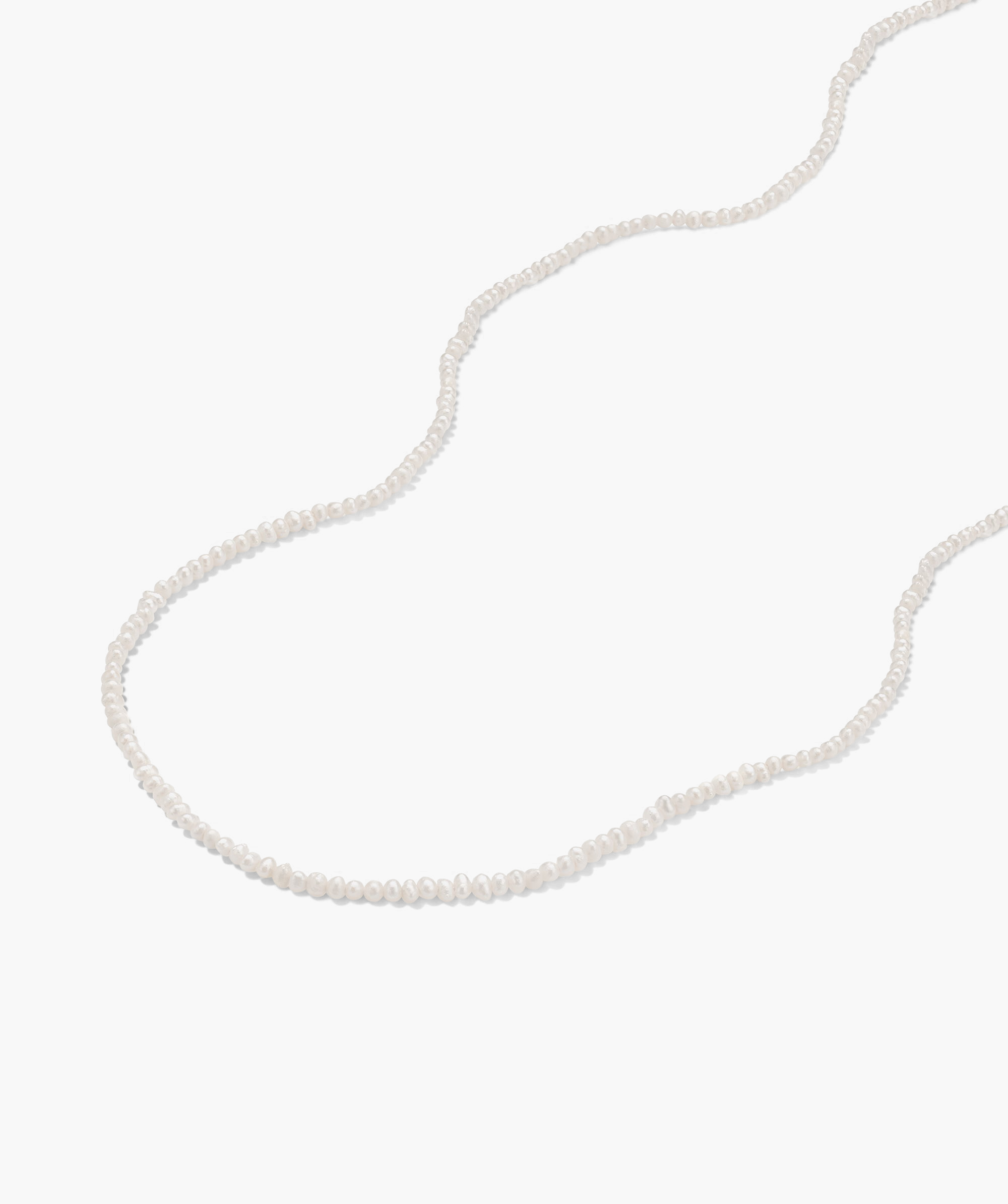 Micro Pearl Necklace on white surface, featuring delicate freshwater pearls and handcrafted in 14k gold, perfect for elevating any outfit.