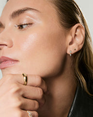 Profile close-up featuring Piercing Studio - Lab Grown Diamond Drop Studs on the earlobe, accompanied by a chunky gold band and textured gold ring on her fingers.
