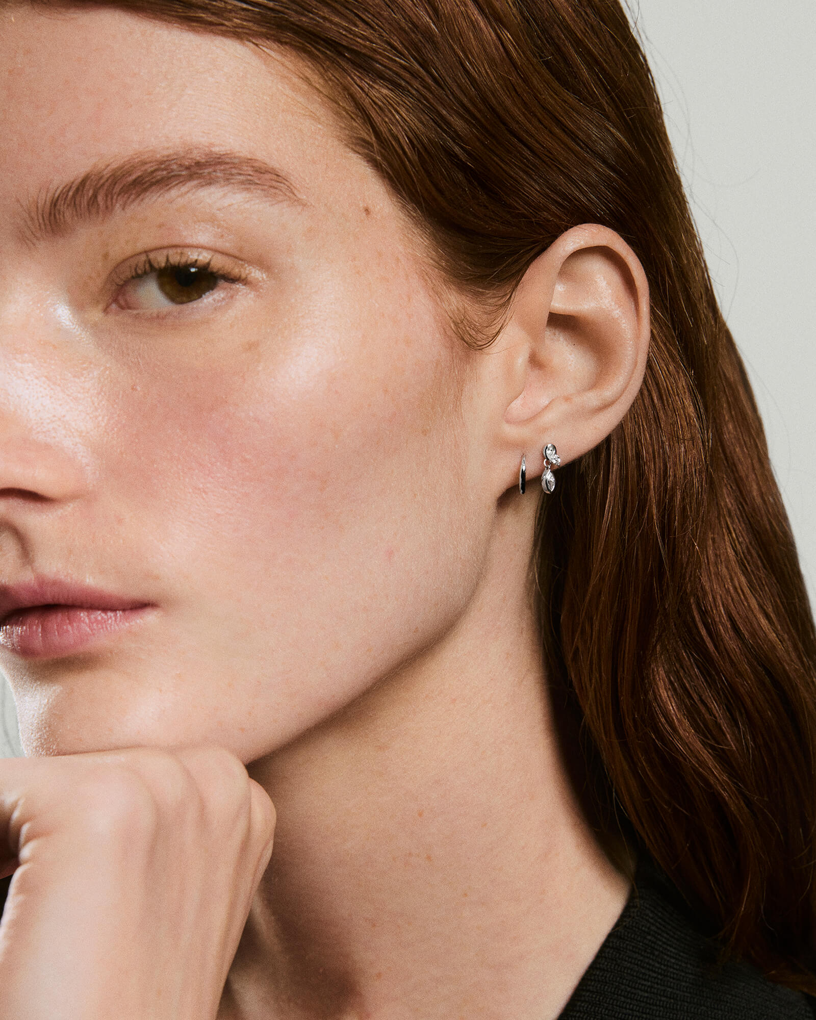 Young woman wearing Piercing Studio - Lab Grown Diamond Drop Studs, featuring a silver hoop and tiny drop earring with clear stones.
