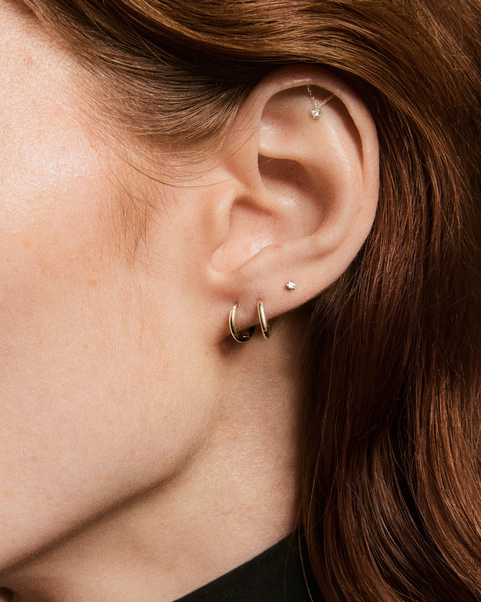 Close-up of a right ear with multiple piercings, showcasing the Piercing Studio - Lab Grown Diamond Helix Stud with a sleek bar, fine chain, and dangling gem.