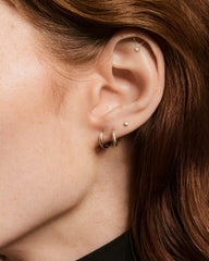 Close-up of a right ear with multiple piercings, showcasing the Piercing Studio - Lab Grown Diamond Helix Stud with a sleek bar, fine chain, and dangling gem.