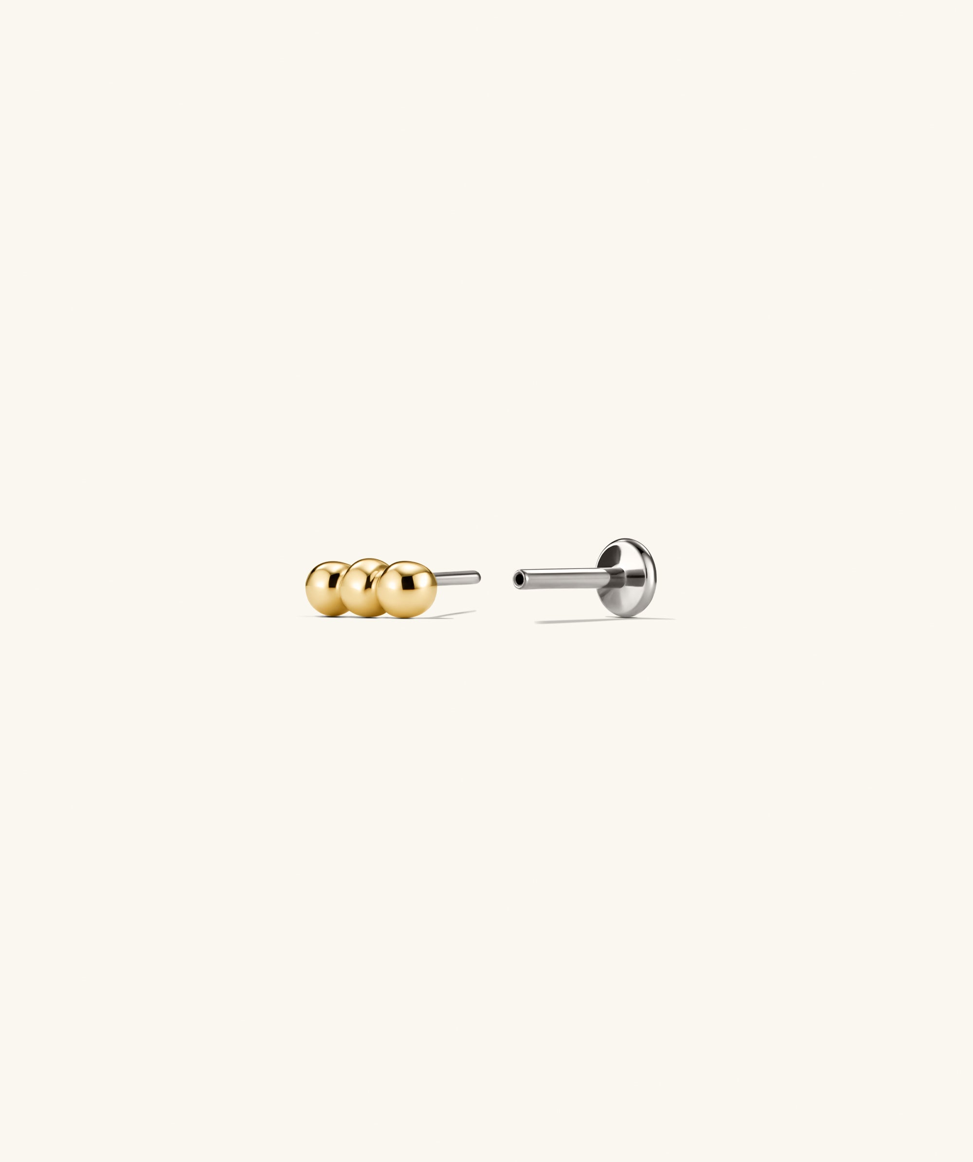 Spheres Bar Stud featuring three gold spheres forming a versatile bar design, ideal for stacking. Comfortable flat back studs with adjustable post sizes for a tailored fit.