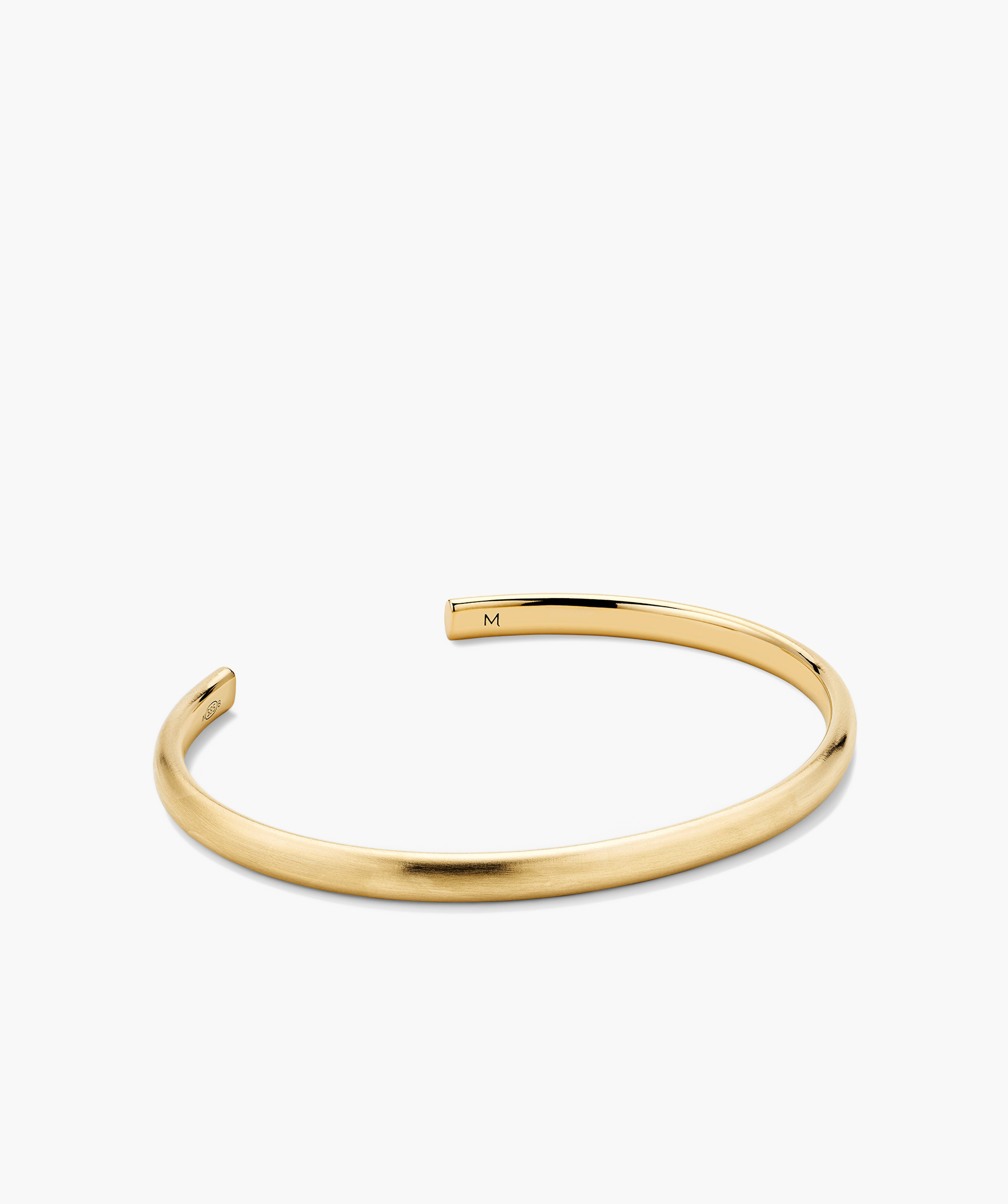 Slim Cuff: A gold bracelet with a minimalist design and an engraved letter M. Ideal for versatile fashion pairings.
