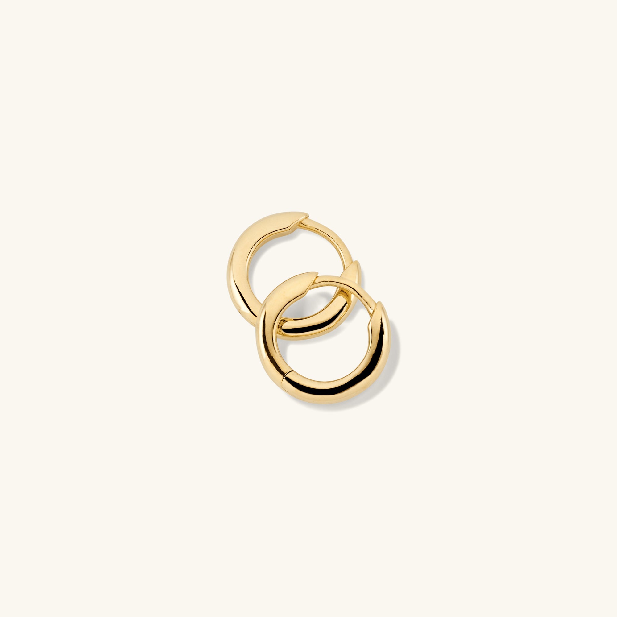 Tube Huggie Hoops: A pair of modern gold hoop earrings with a clicker closure, designed to be bold yet lightweight for comfortable wear.