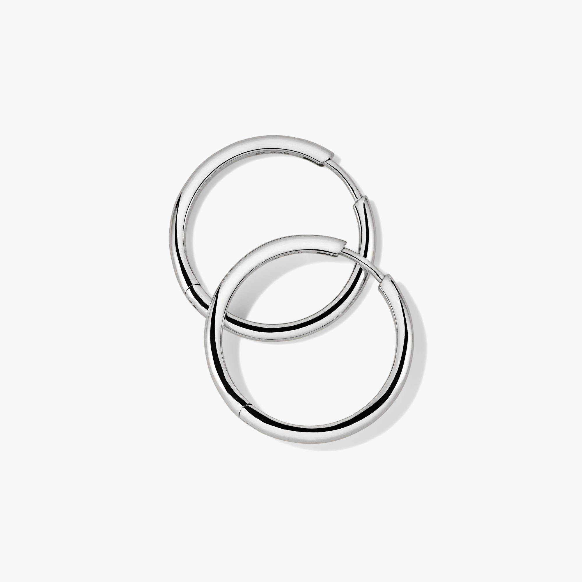 Tube Large Hoops: A pair of modern, lightweight silver hoop earrings with a clicker closure for comfort and security, designed as bold fashion accessories.