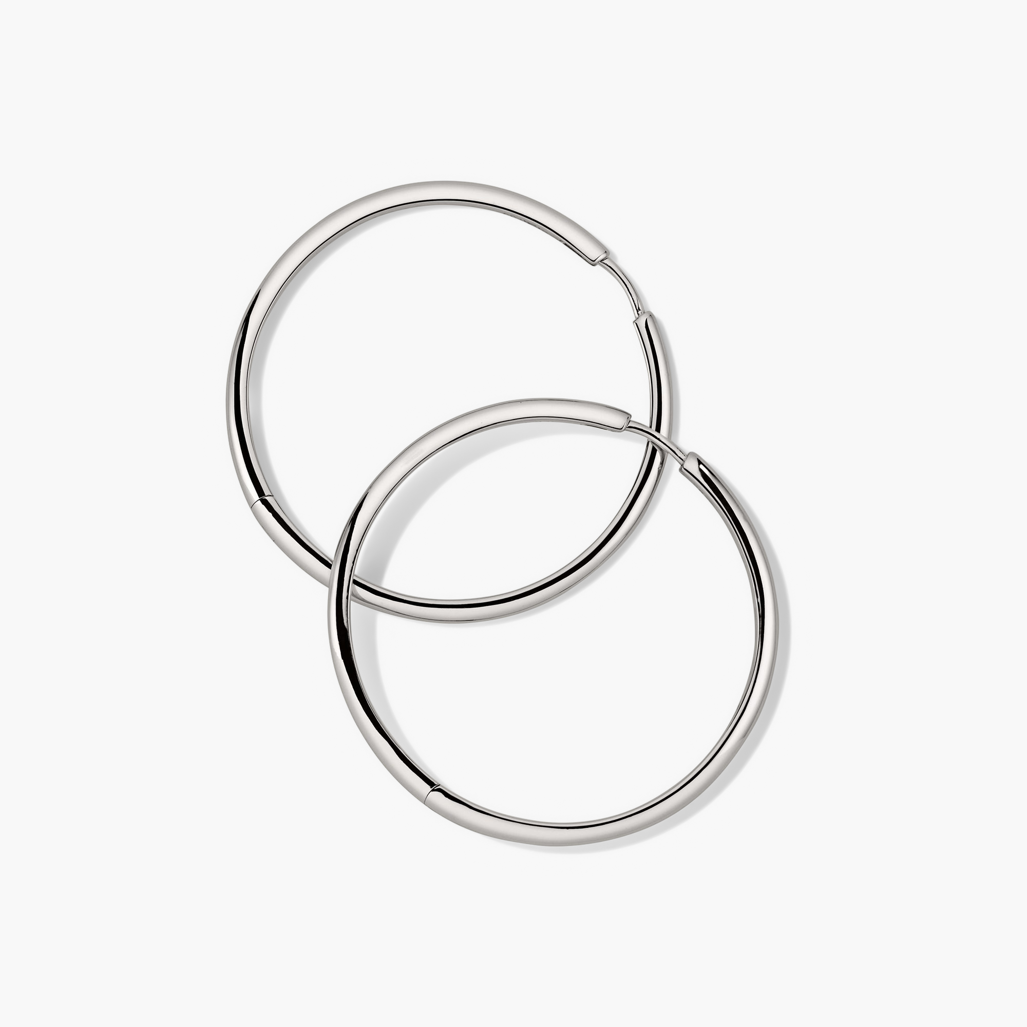 Tube Oversized Hoops: A pair of bold, silver hoop earrings with a clicker closure, designed for modern style and lightweight comfort.