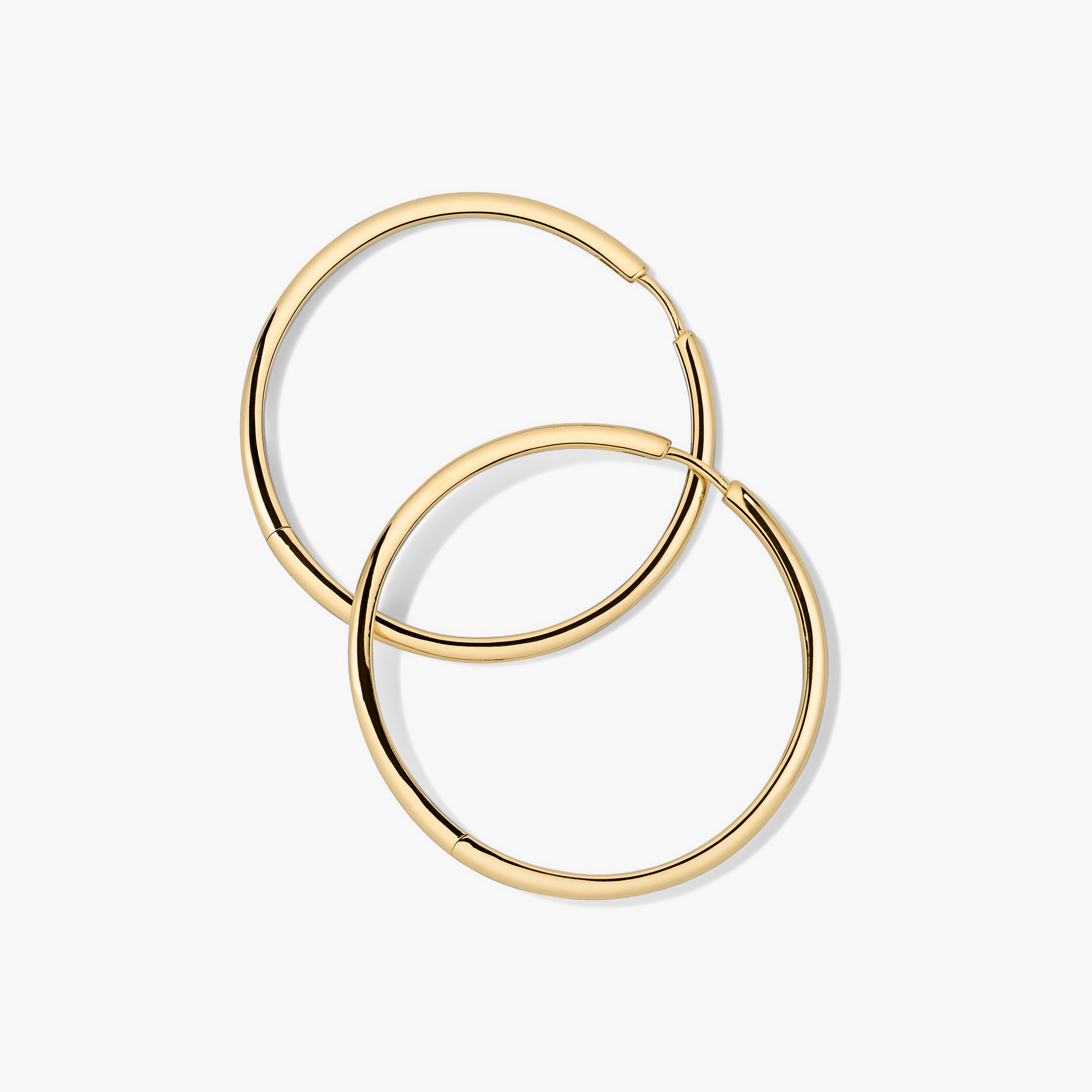 Tube Oversized Hoops: A pair of modern, lightweight gold hoop earrings with a clicker closure, designed for effortless wear and maximum comfort.