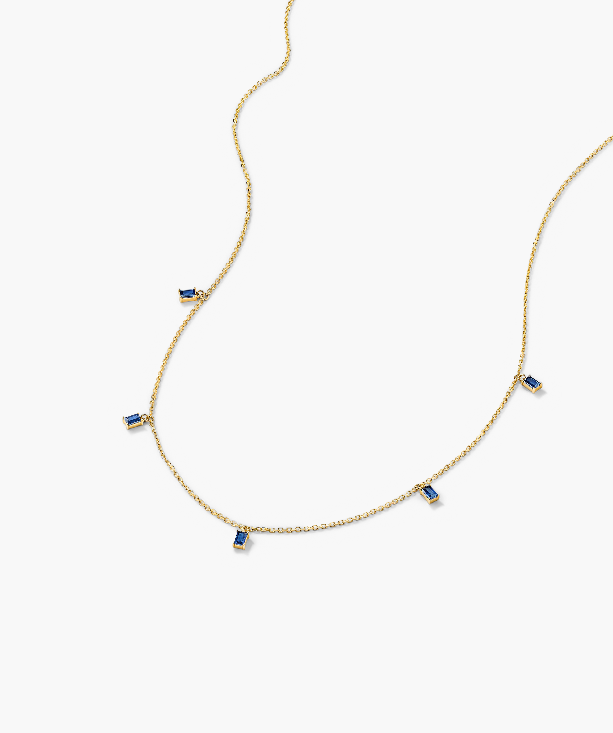 Baguette Gemstone Station Necklace: a gold chain adorned with evenly spaced blue gems, perfect for elegant stacking and adding a touch of shine to any outfit.