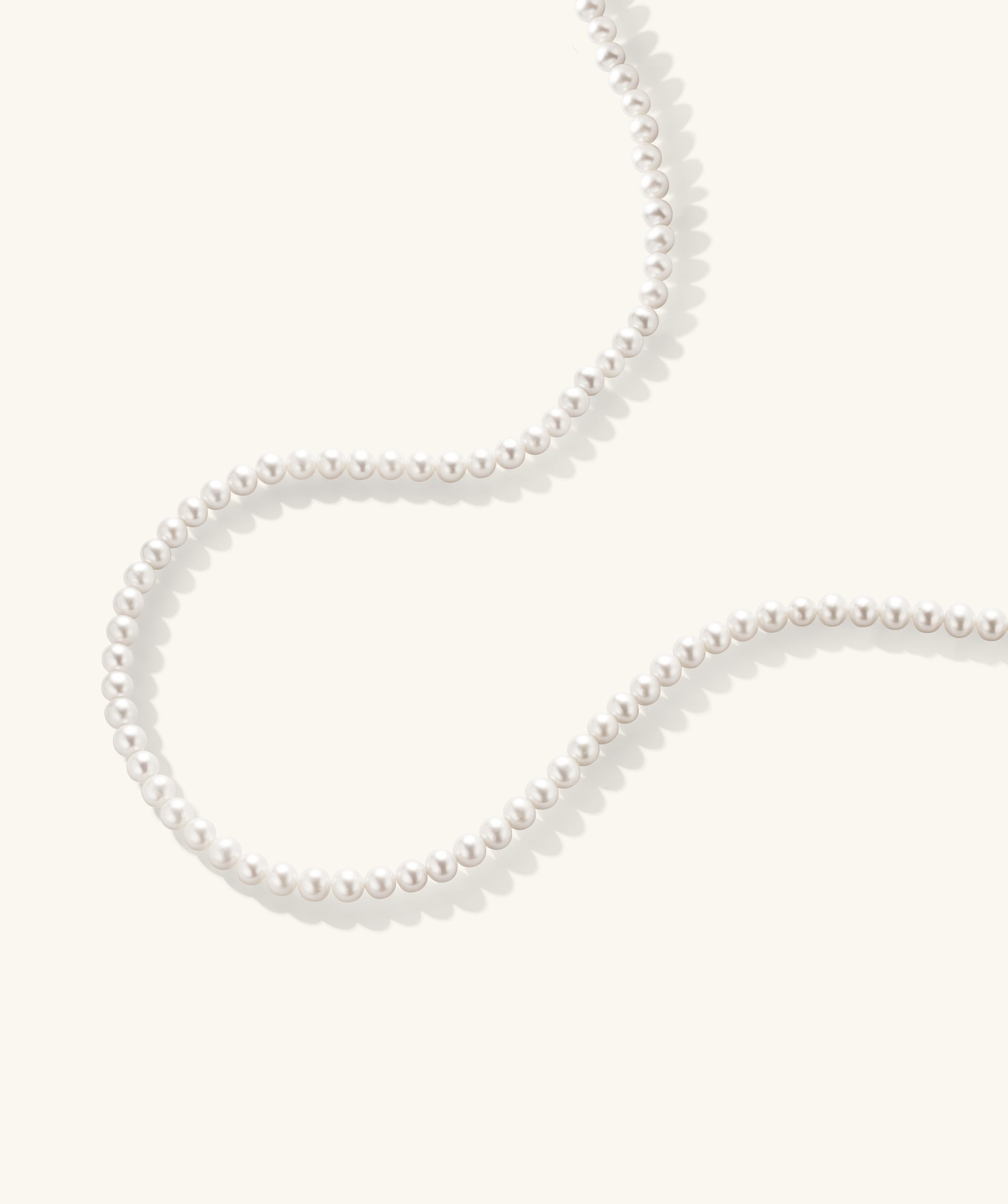 Paradigm Pearl Necklace: A handcrafted string of freshwater pearls with a sterling silver clasp, displayed on a white surface.