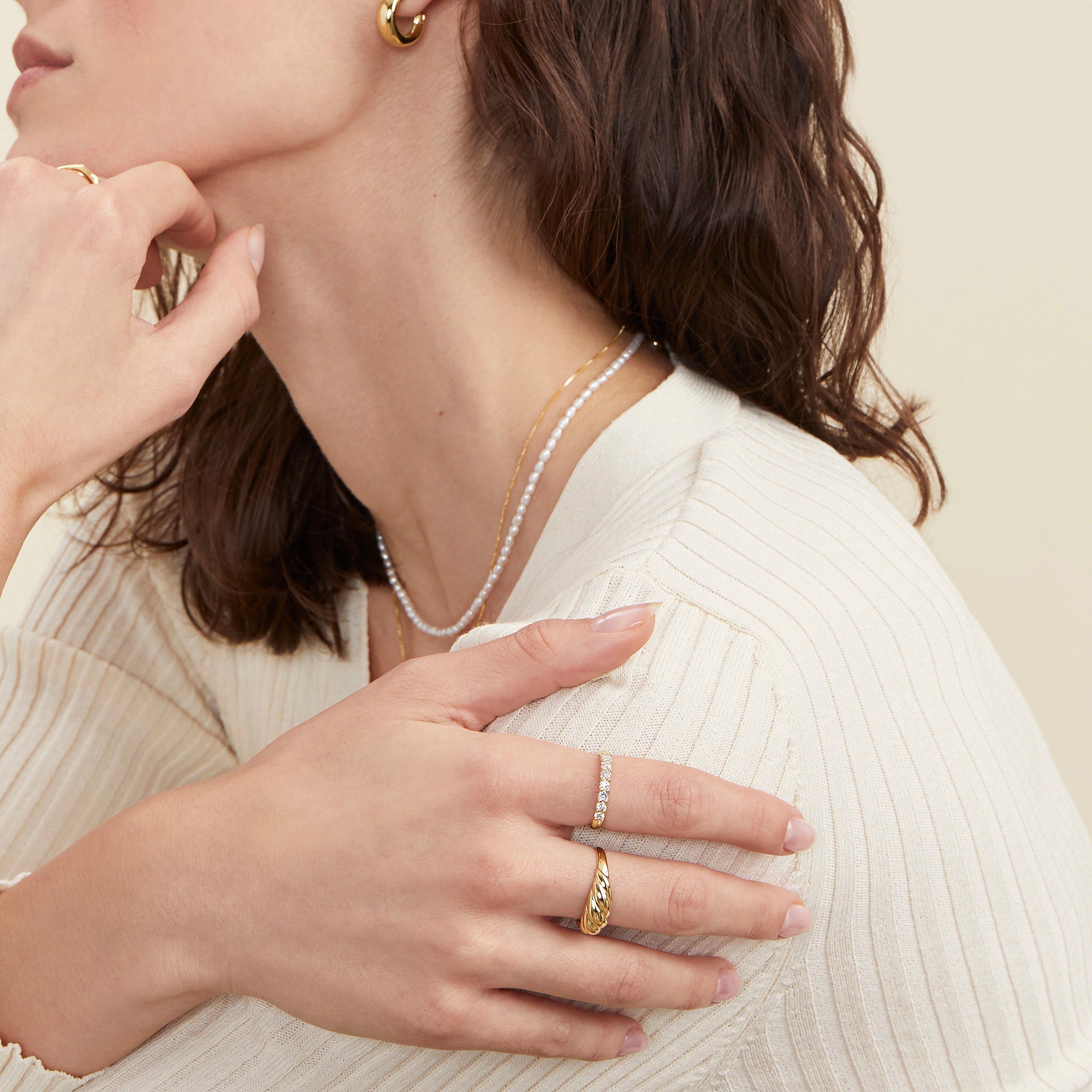 Woman wearing a white sweater and gold jewelry showcases the Bold Diamond Half Eternity Ring, a handcrafted 14k gold ring with seven round cut diamonds.