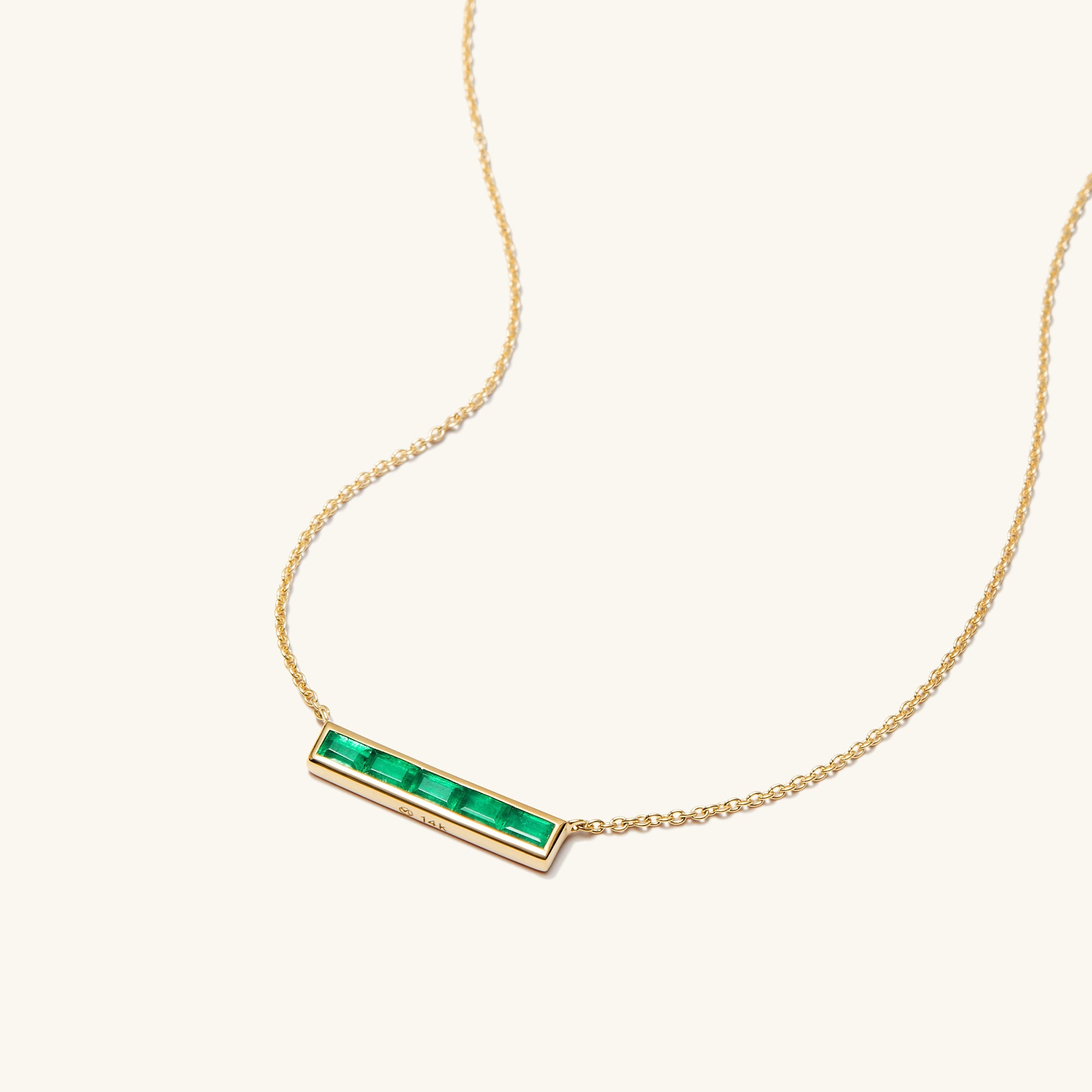 Baguette Emerald Bar Necklace: A gold necklace featuring a handcrafted, tapered baguette emerald pendant on a delicate 14k solid gold chain.