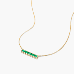 Baguette Emerald Bar Necklace: A gold necklace featuring a handcrafted, tapered baguette emerald pendant on a delicate 14k solid gold chain.