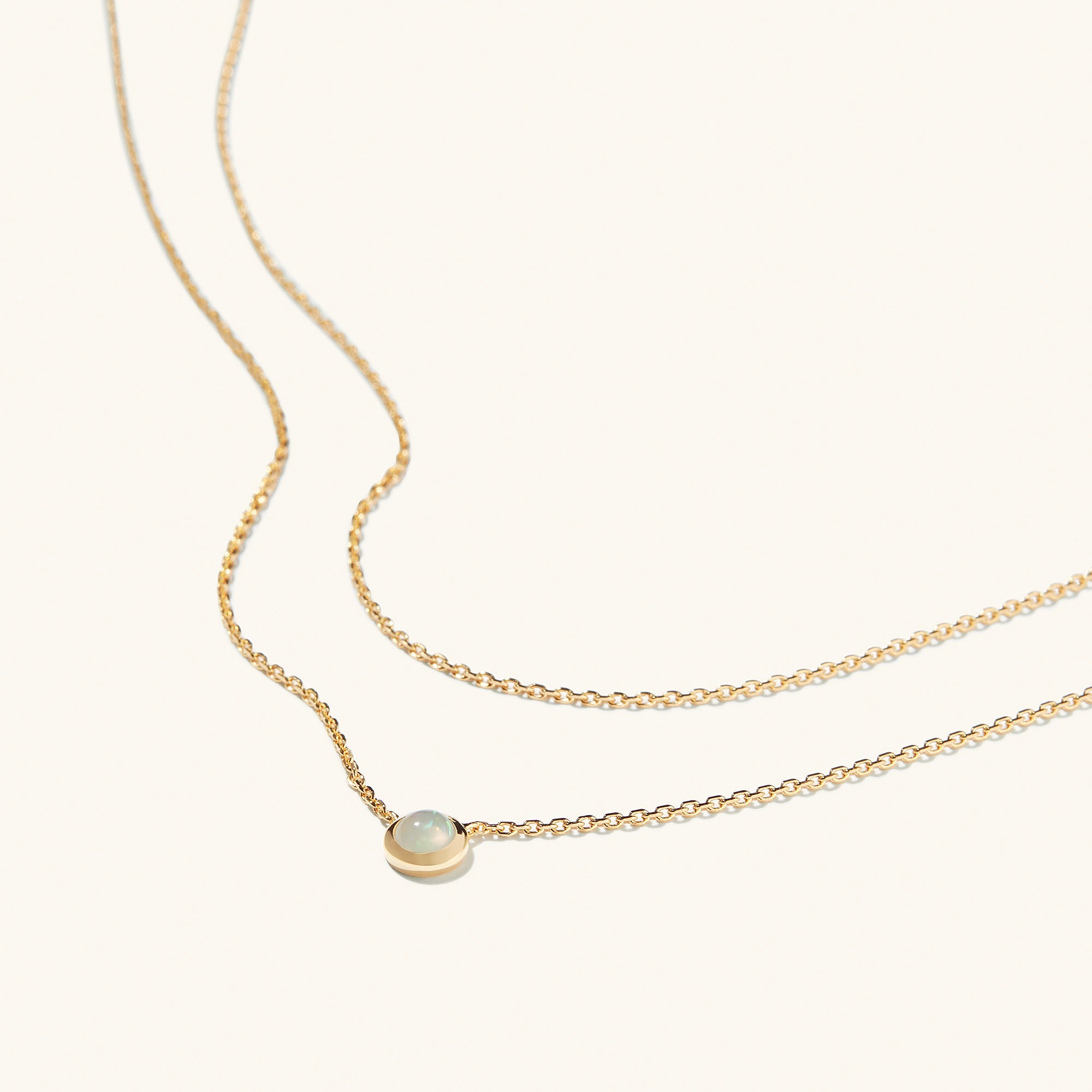 Layered Opal Necklace featuring a gold chain with a natural opal pendant in the center.
