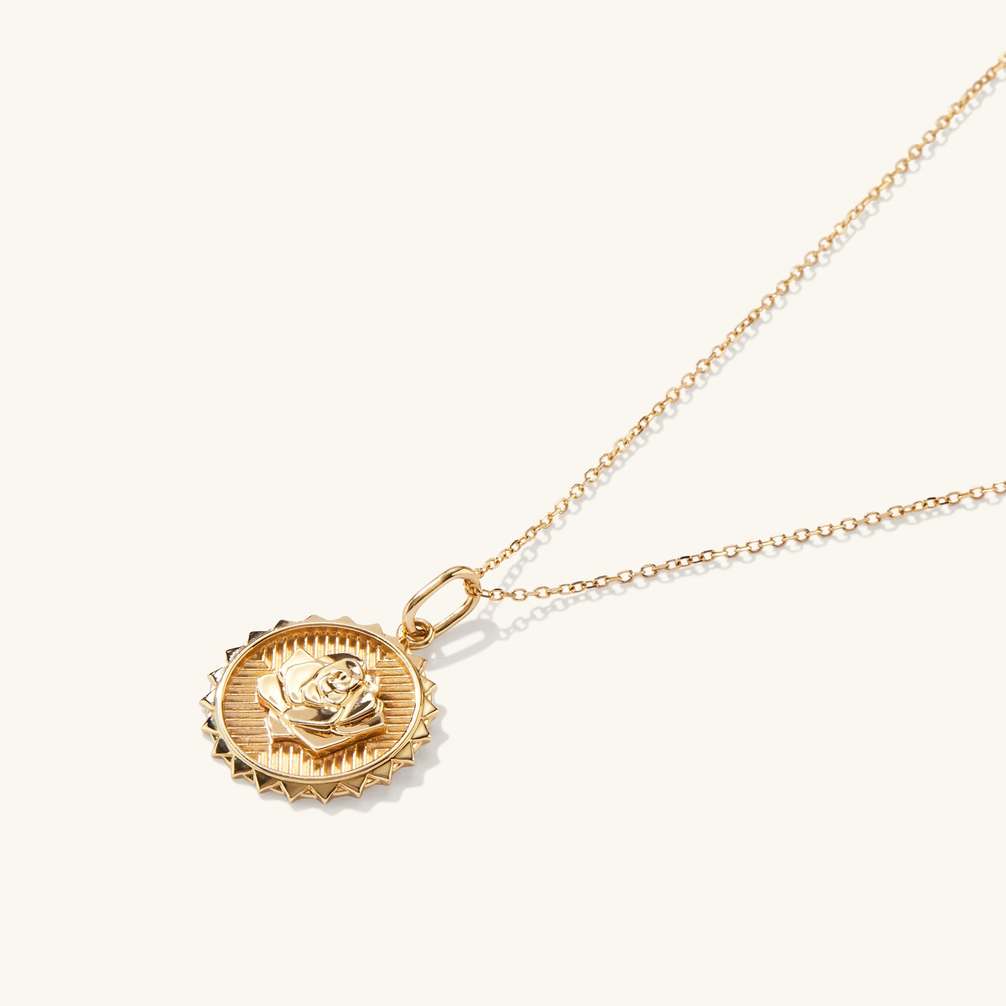 Strength: Rose Coin Charm Pendant featuring a gold medallion with an embossed rose, hanging from a delicate gold chain. Handcrafted in recycled 14k solid gold.
