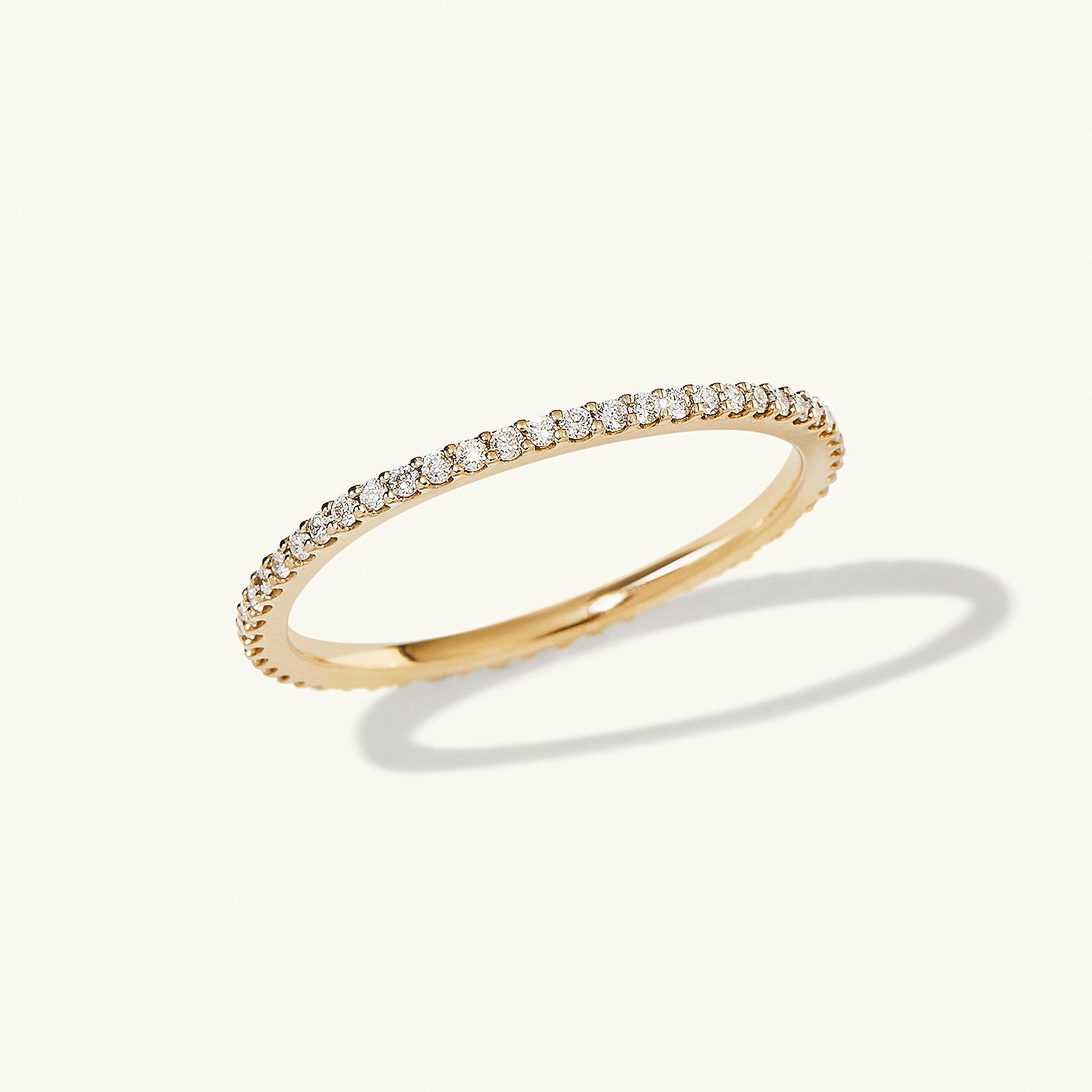 Slim Diamond Eternity Band: Close-up of a gold ring featuring 47-60 hand-set diamonds in open prongs, highlighting its delicate, sparkling design.