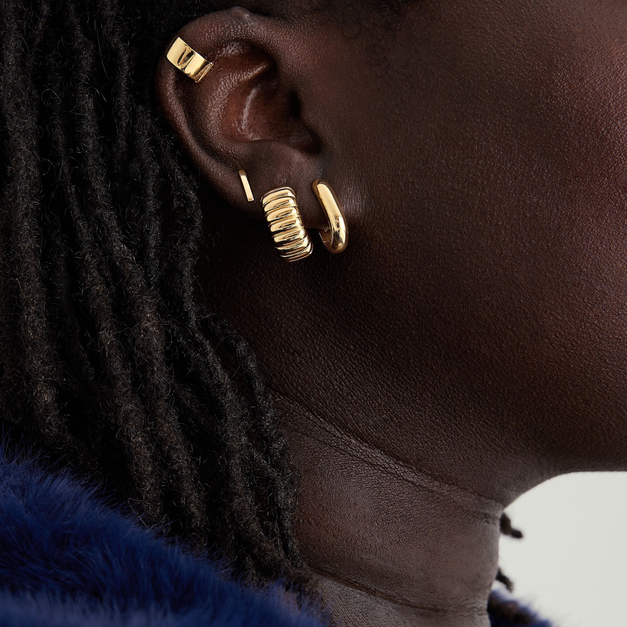 Close-up of a woman's ear showcasing Mixed Convertible Link Earrings, handcrafted in 18k gold vermeil and sterling silver, styled as huggies.