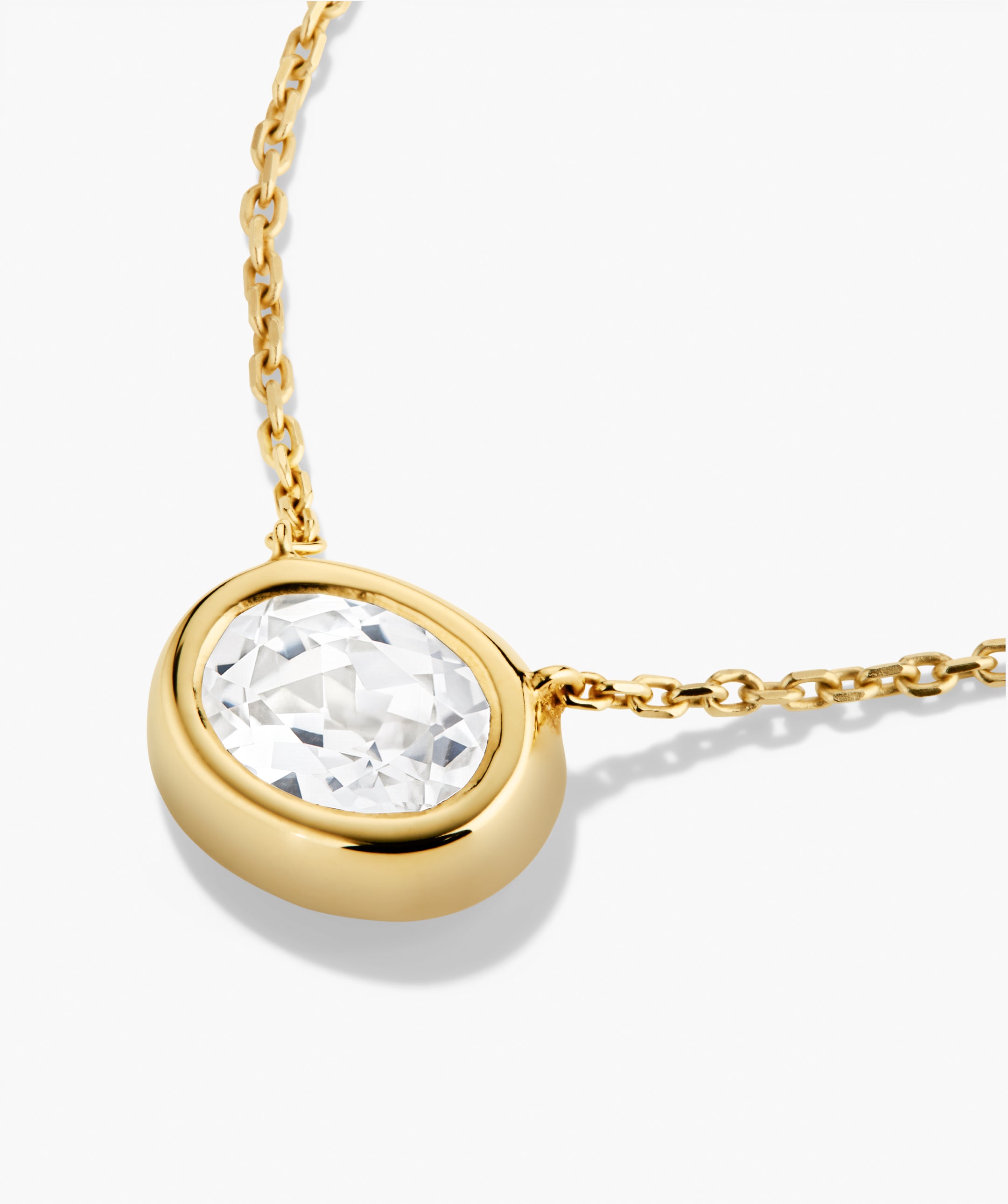 Lucia Necklace featuring a bezel-set, oval faceted clear stone pendant on a simple cable-link chain, embodying elegance and signature style.