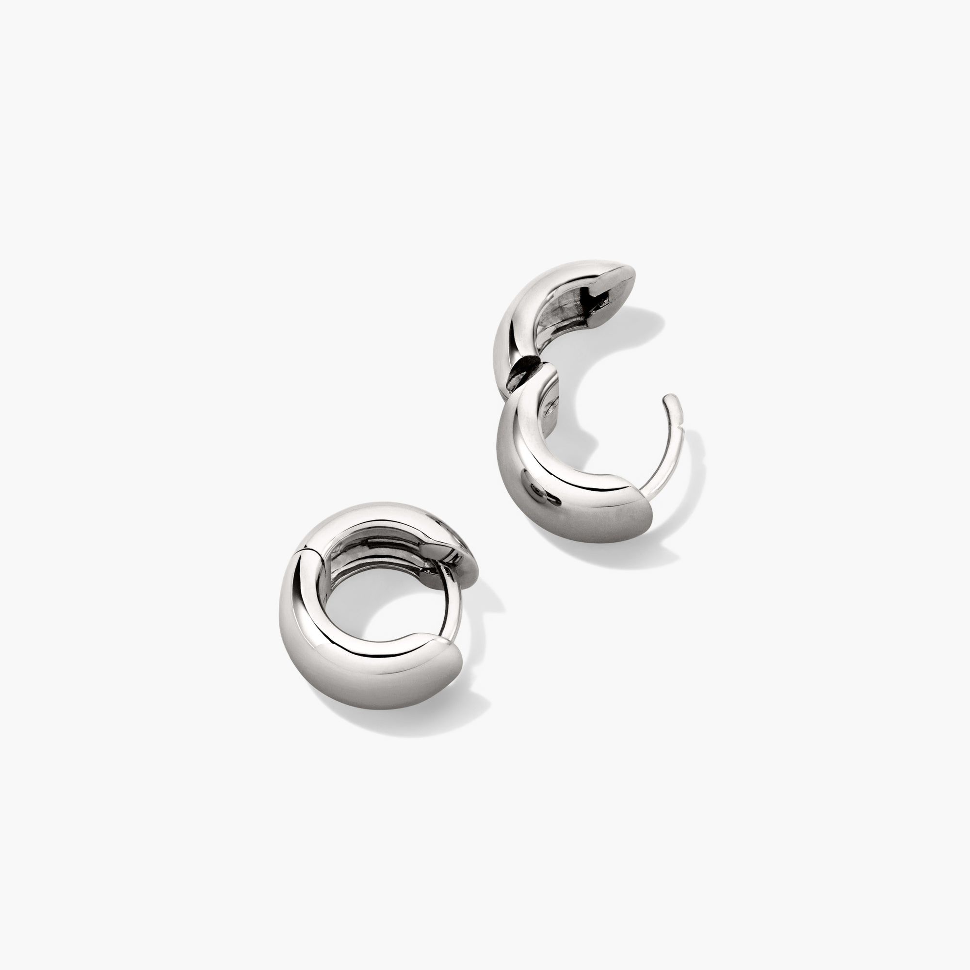 Chunky Huggie Hoops: A close-up of a pair of silver, chunky, curved-design earrings with a clicker closure for comfort and security.