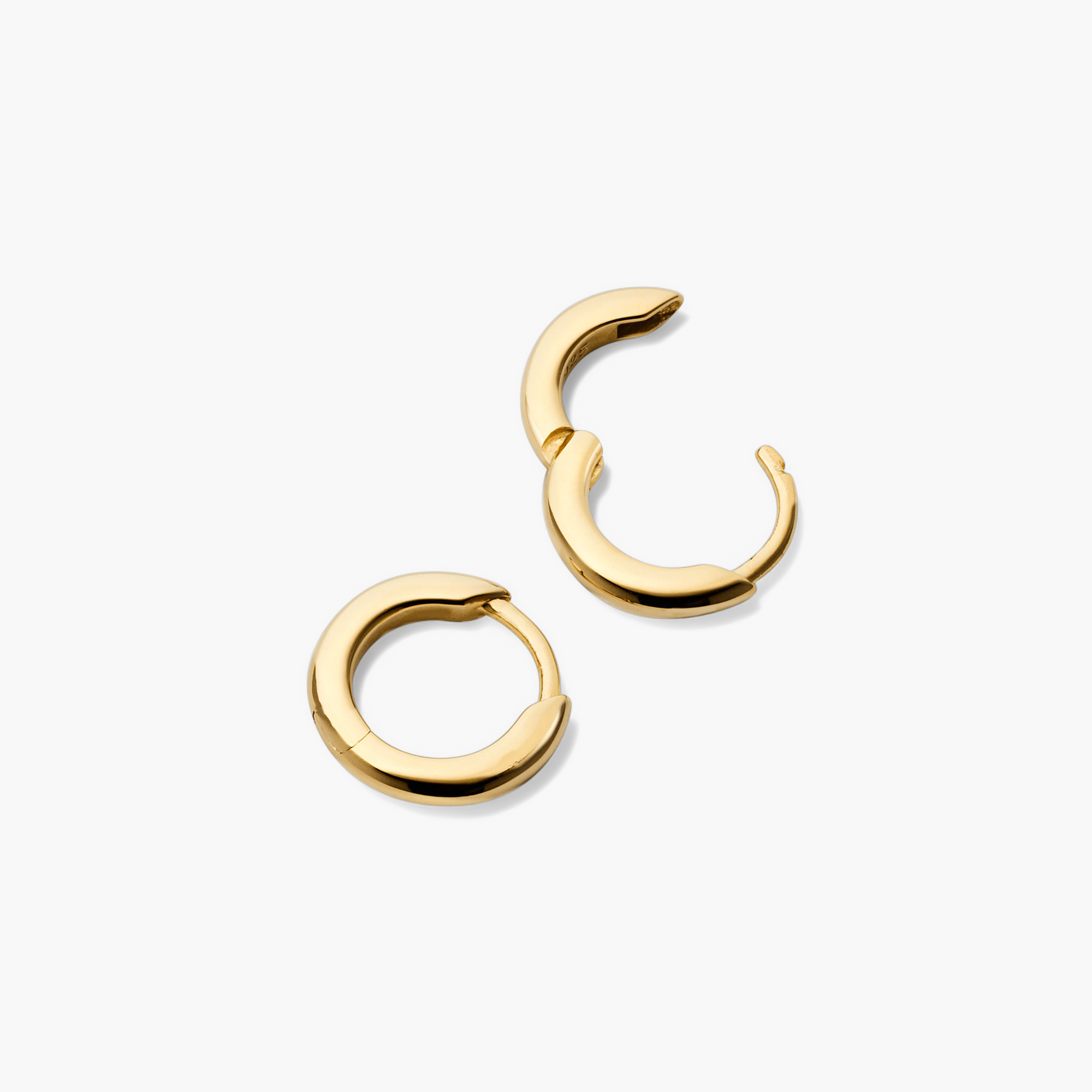 Tube Huggie Hoops: A pair of modern gold hoop earrings with a clicker closure for comfort and security, designed in a lightweight, bold tube style.