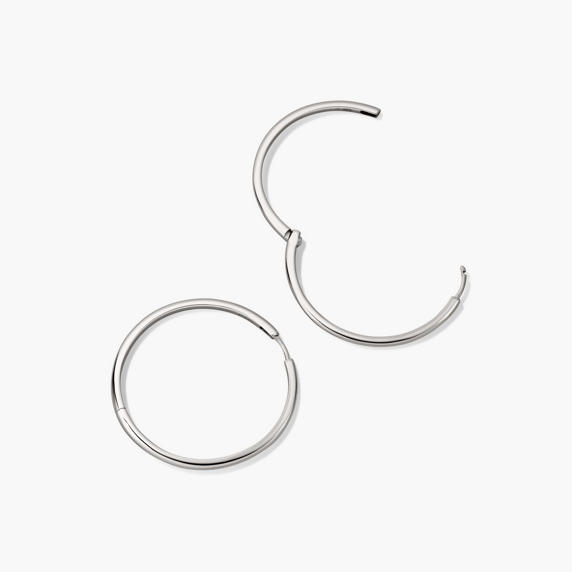 Tube Oversized Hoops: A pair of bold silver hoop earrings with a clicker closure, designed for comfort and security, showcasing a modern tubular style.
