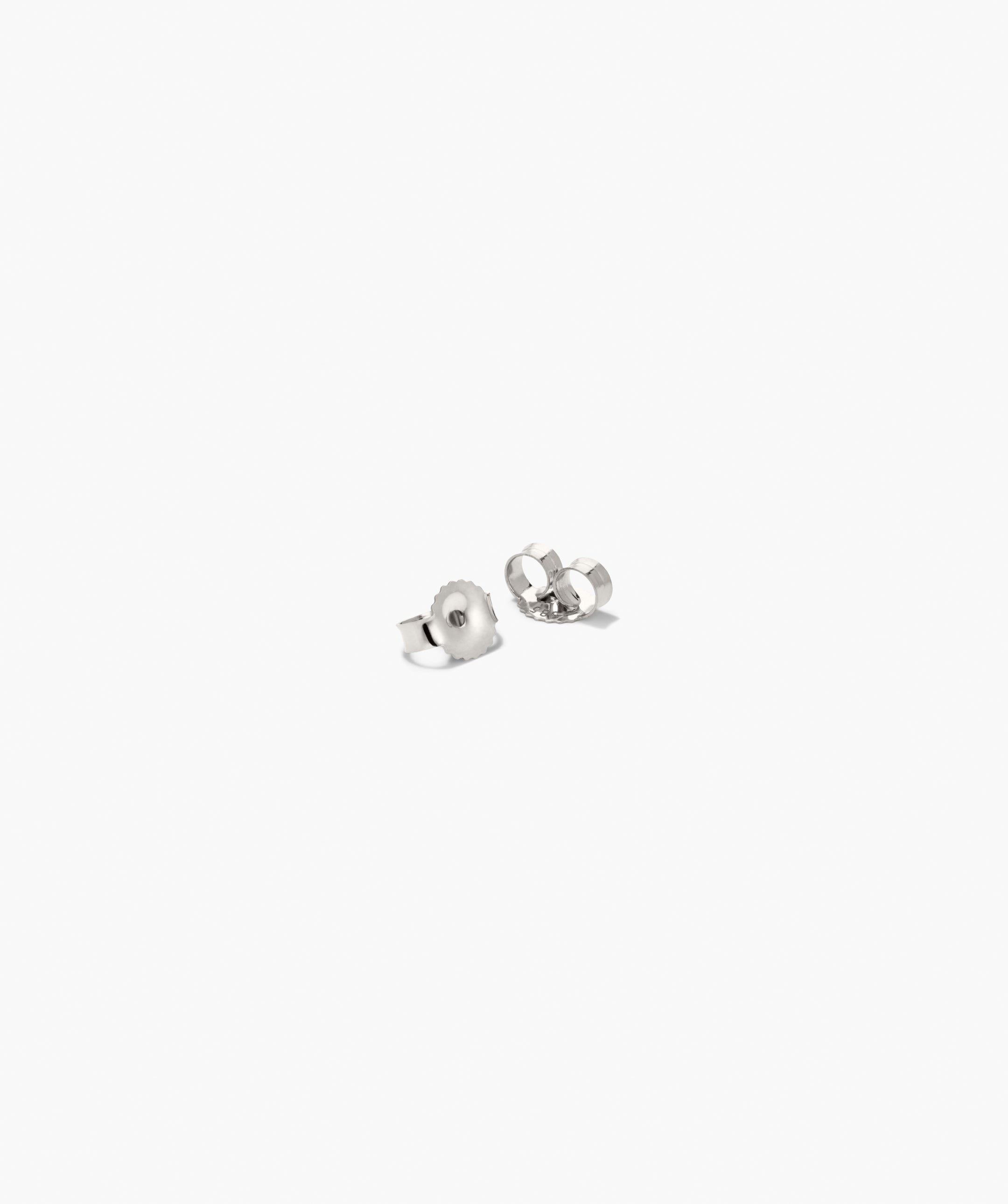 Bold Open DÃ´me Huggies: small silver-tone earring backs with a textured, asymmetrical design, offering a striking yet understated look against a white background.