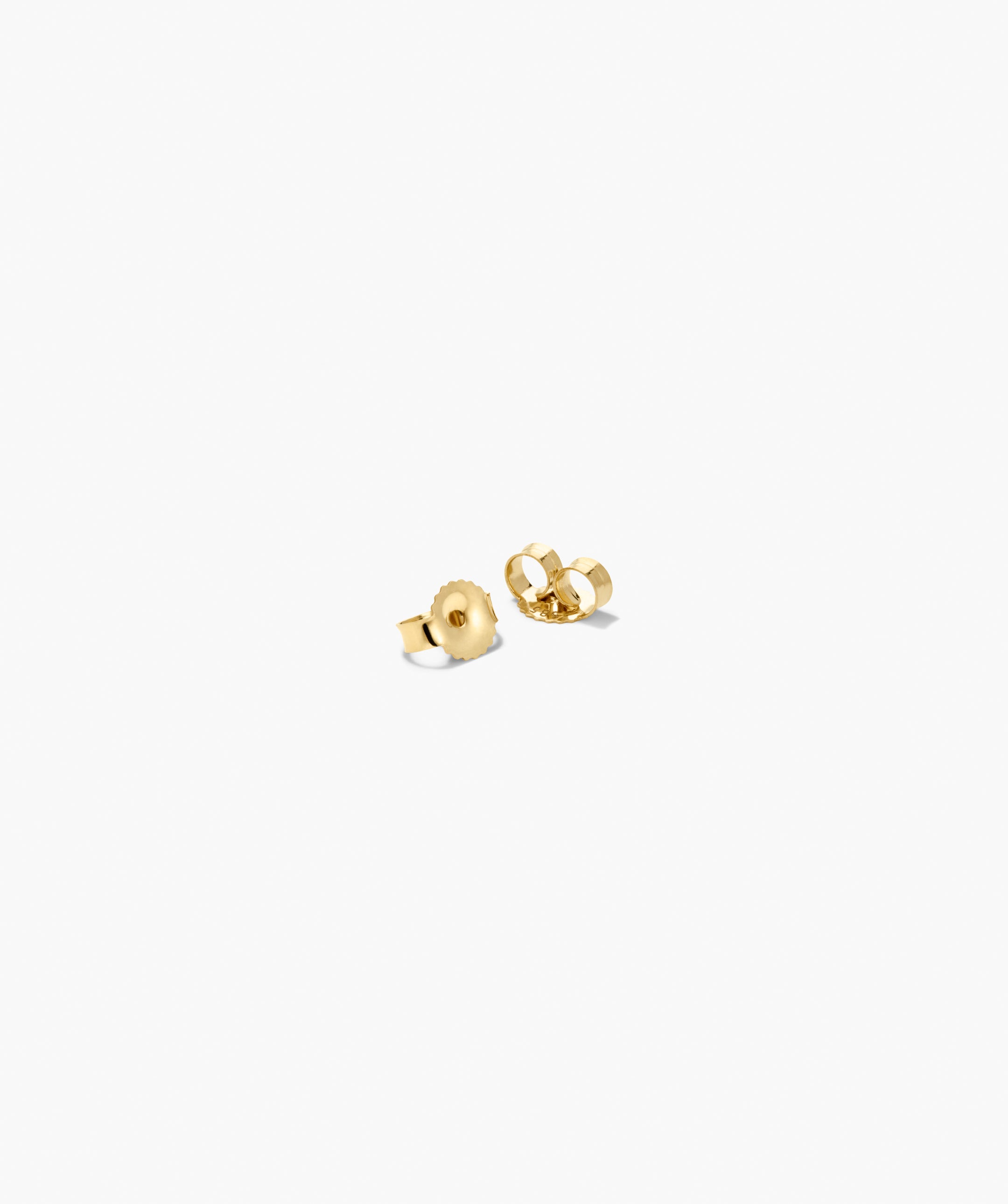 Two small gold-tone earring backs for securing stud earrings, complementing the Bold Open DÃ´me Huggies' understated, textured, and asymmetrical design.